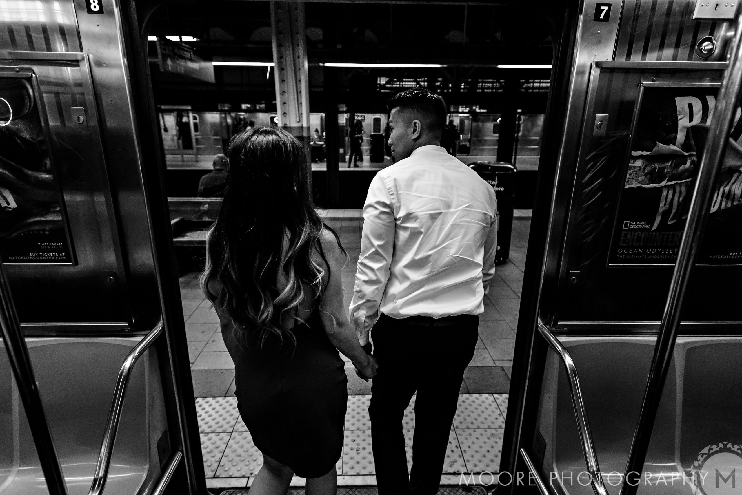 Romantic couple holding hands exiting a subway train, NYC engagement in black and white.
