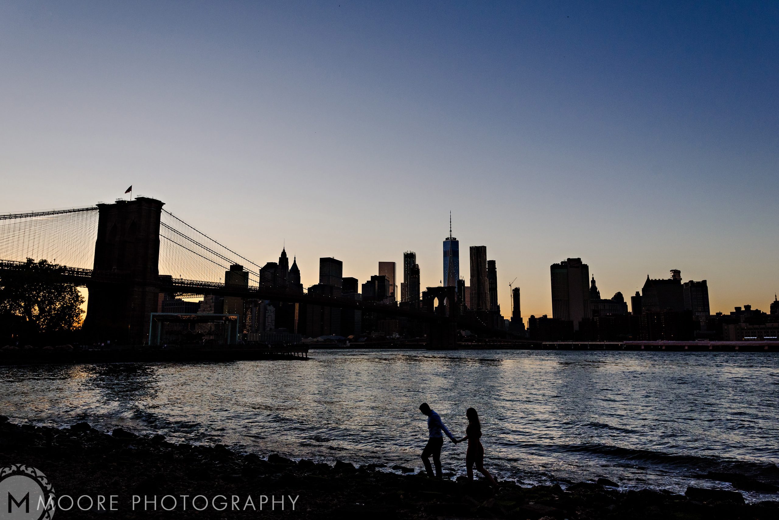 Silhouetted couple in a romantic NYC scene by the river at dusk.