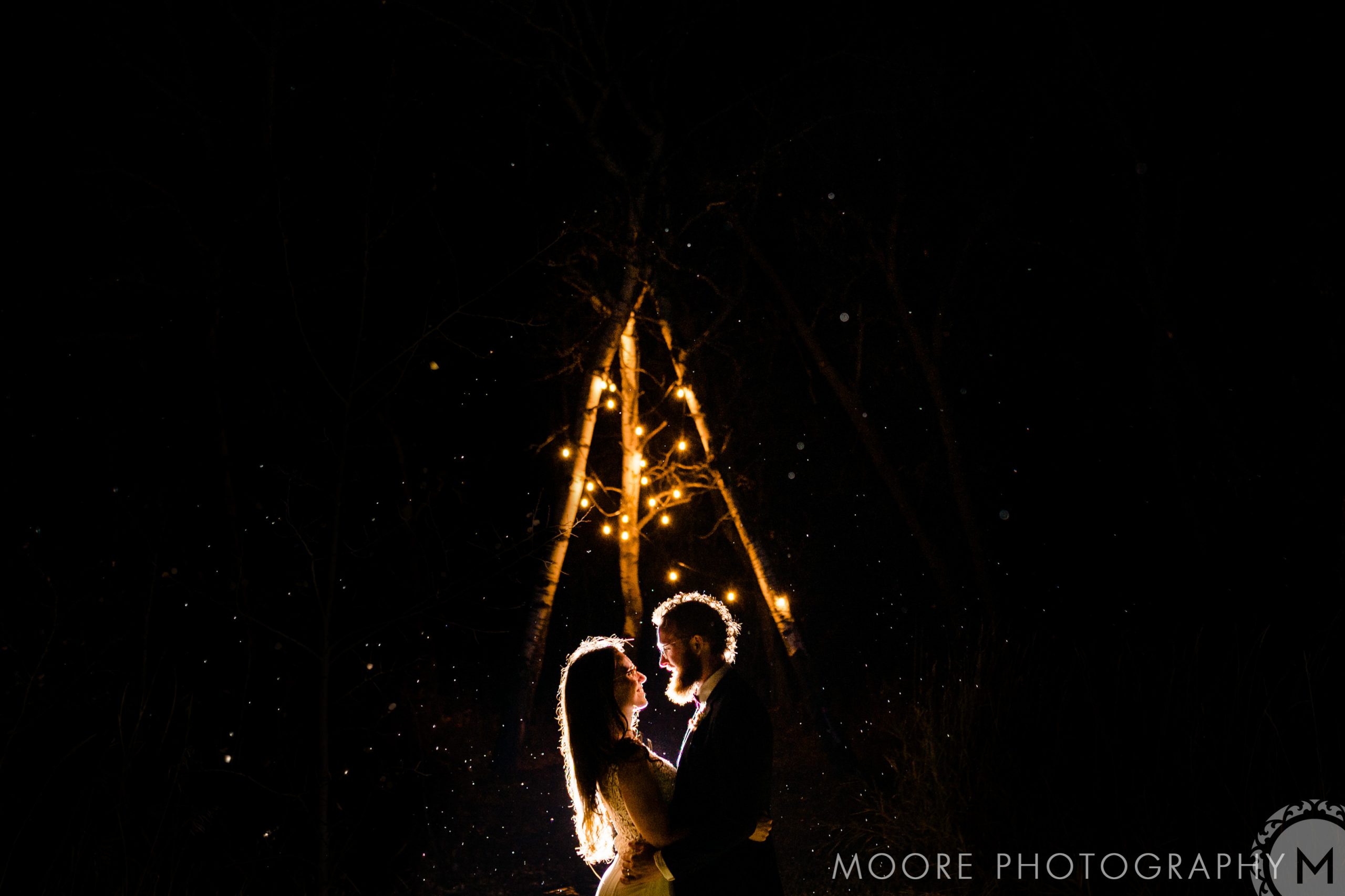Couple embraces under twinkling lights at night, a starry Winnipeg wedding venue backdrop.