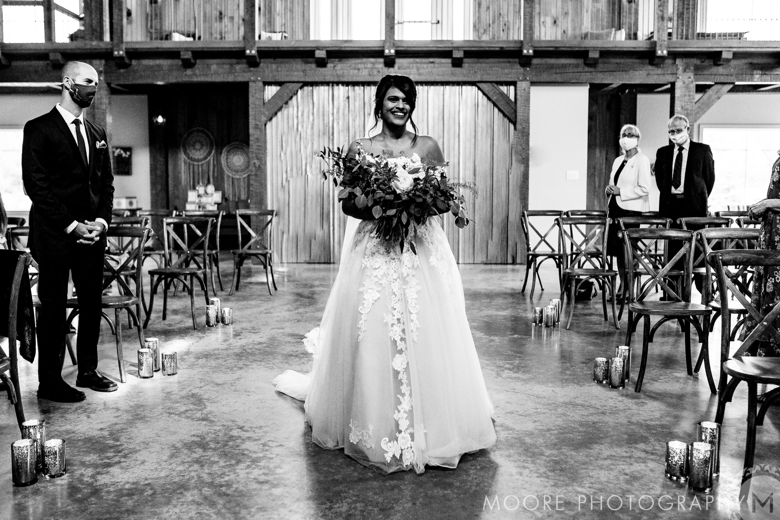 Bride walking down the aisle in a Winnipeg wedding venue, carrying a bouquet and in a gown.