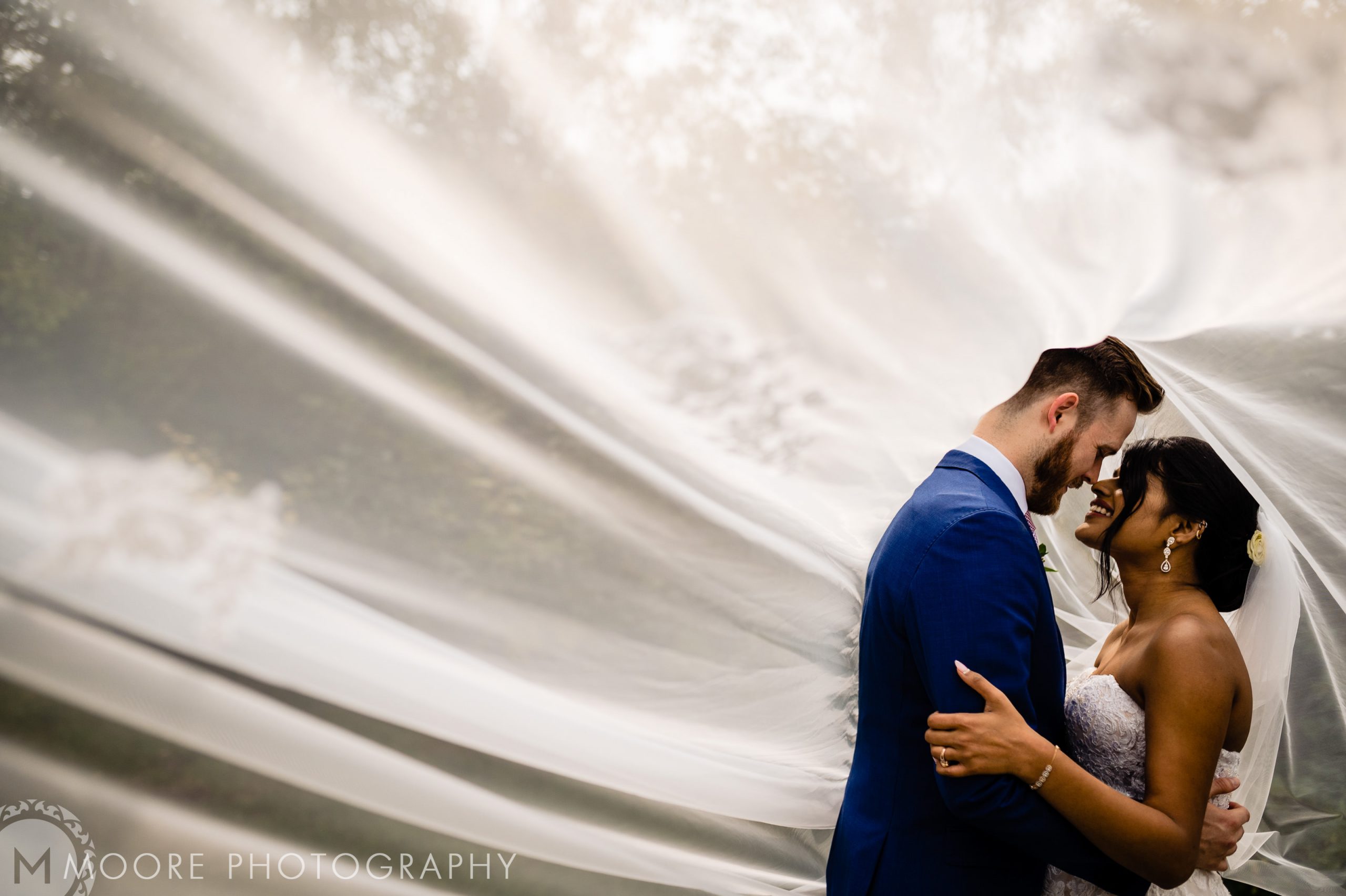 Bride and groom embrace under veil, creating a romantic scene at Winnipeg wedding venues.
