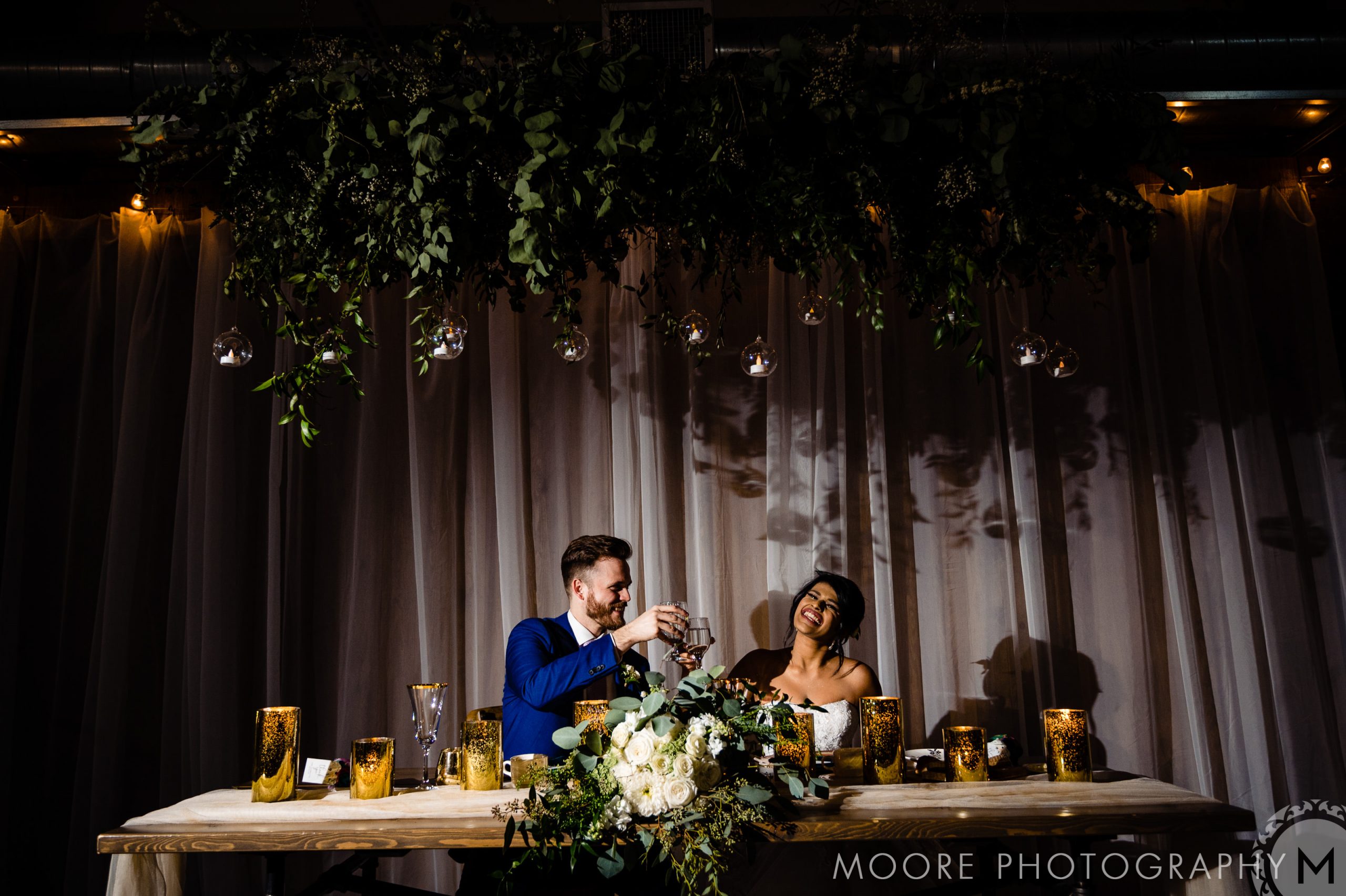 Couple laughing at a decorated table under greenery at Winnipeg wedding venues.