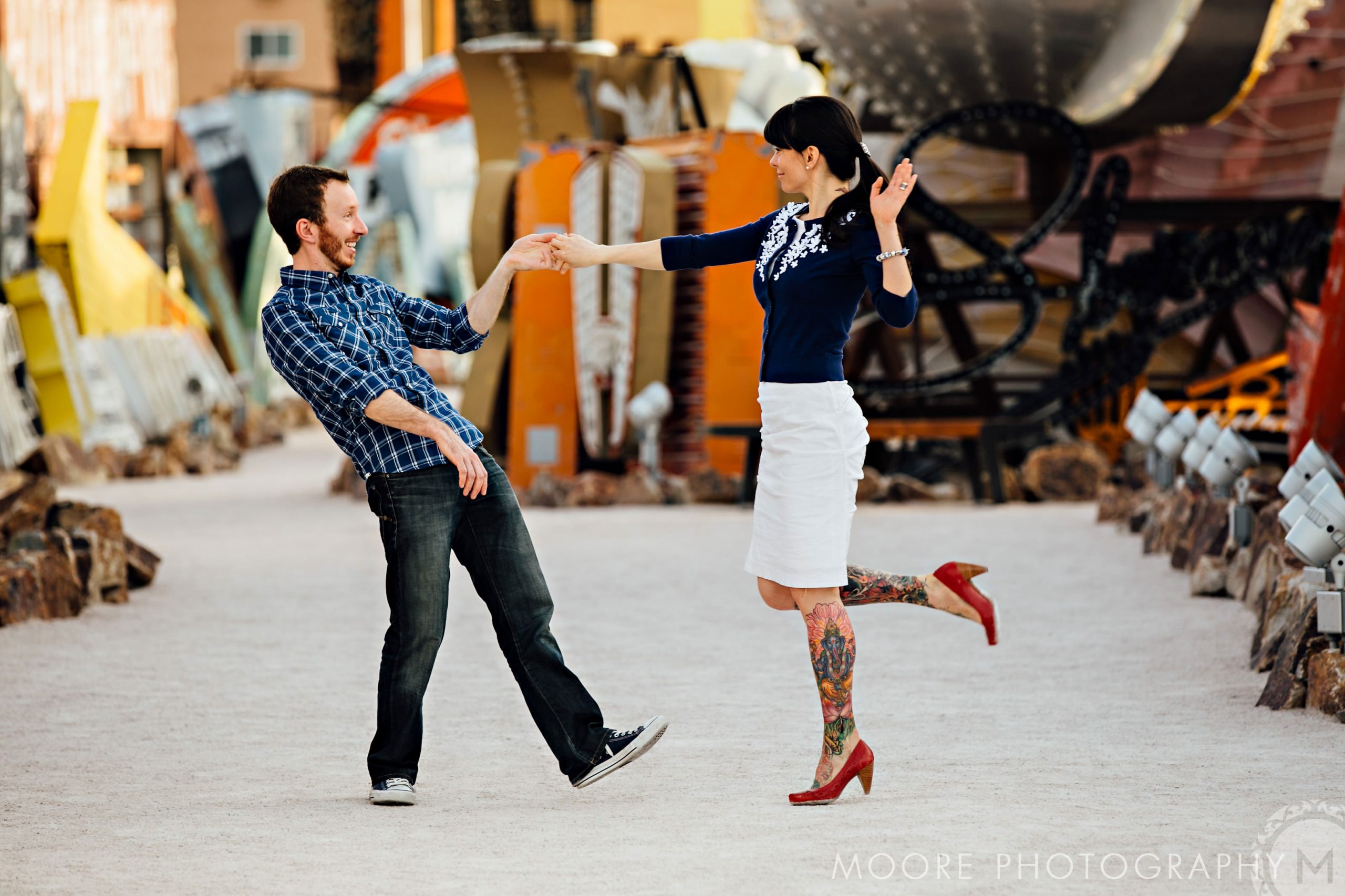 A couple joyfully dances on a sunlit path, perfect for destination wedding photography.