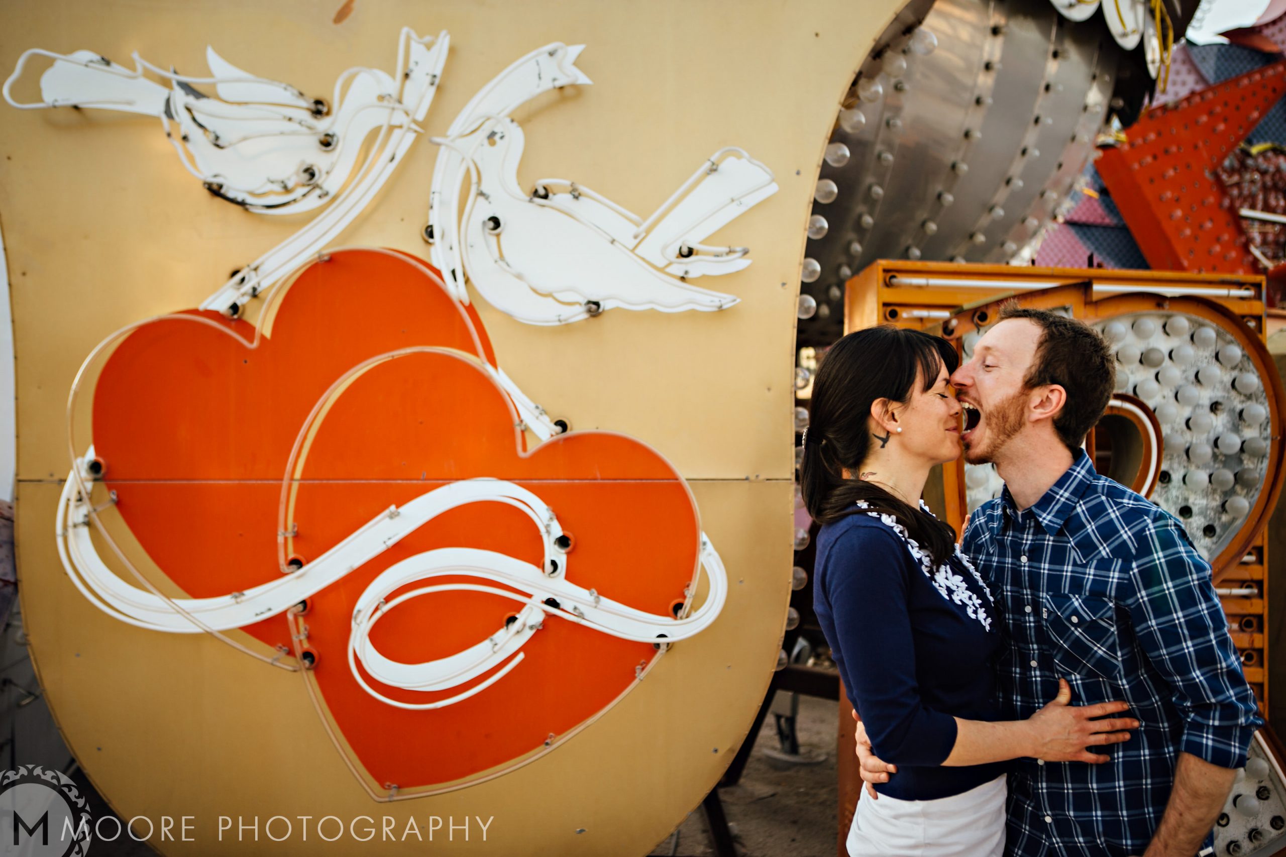 Couple kissing in front of a retro sign, perfect for destination wedding photography.