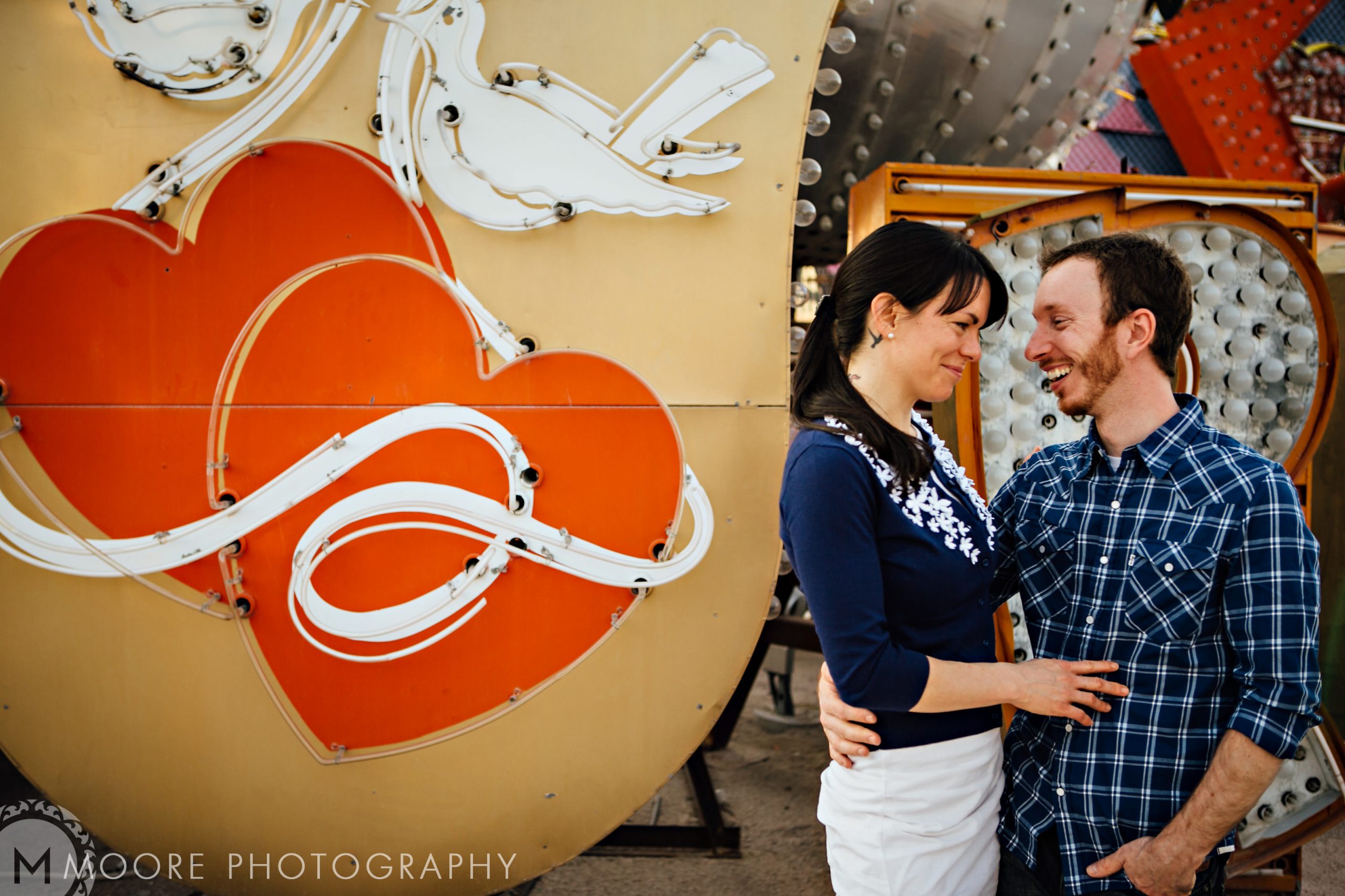 Couple beaming in front of a neon-lit heart, captured perfectly for destination wedding photography.