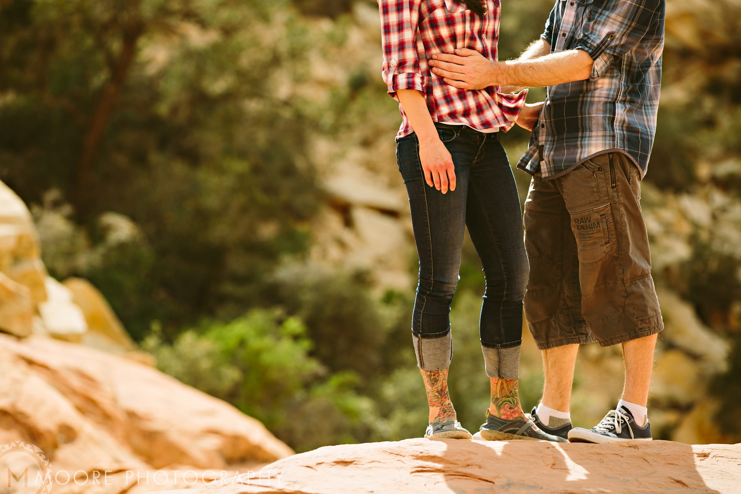 Two people on a rock, holding hands in plaid, capture destination wedding moments.