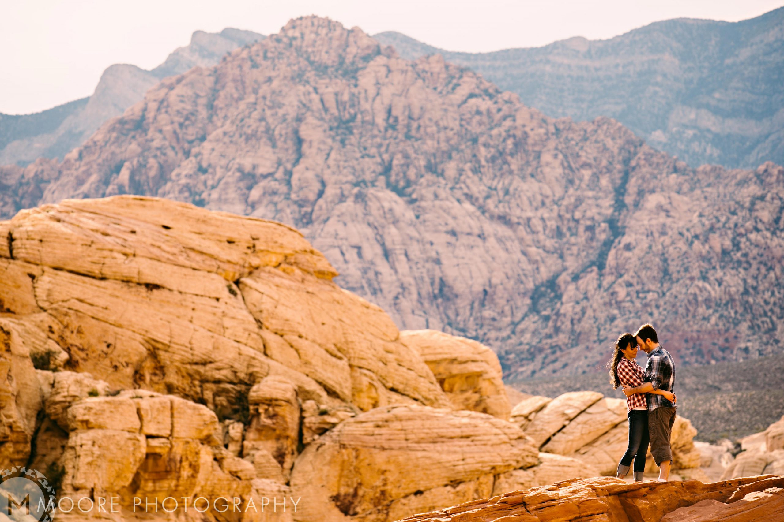 A couple embraces on rocky terrain, perfect for destination wedding photography.