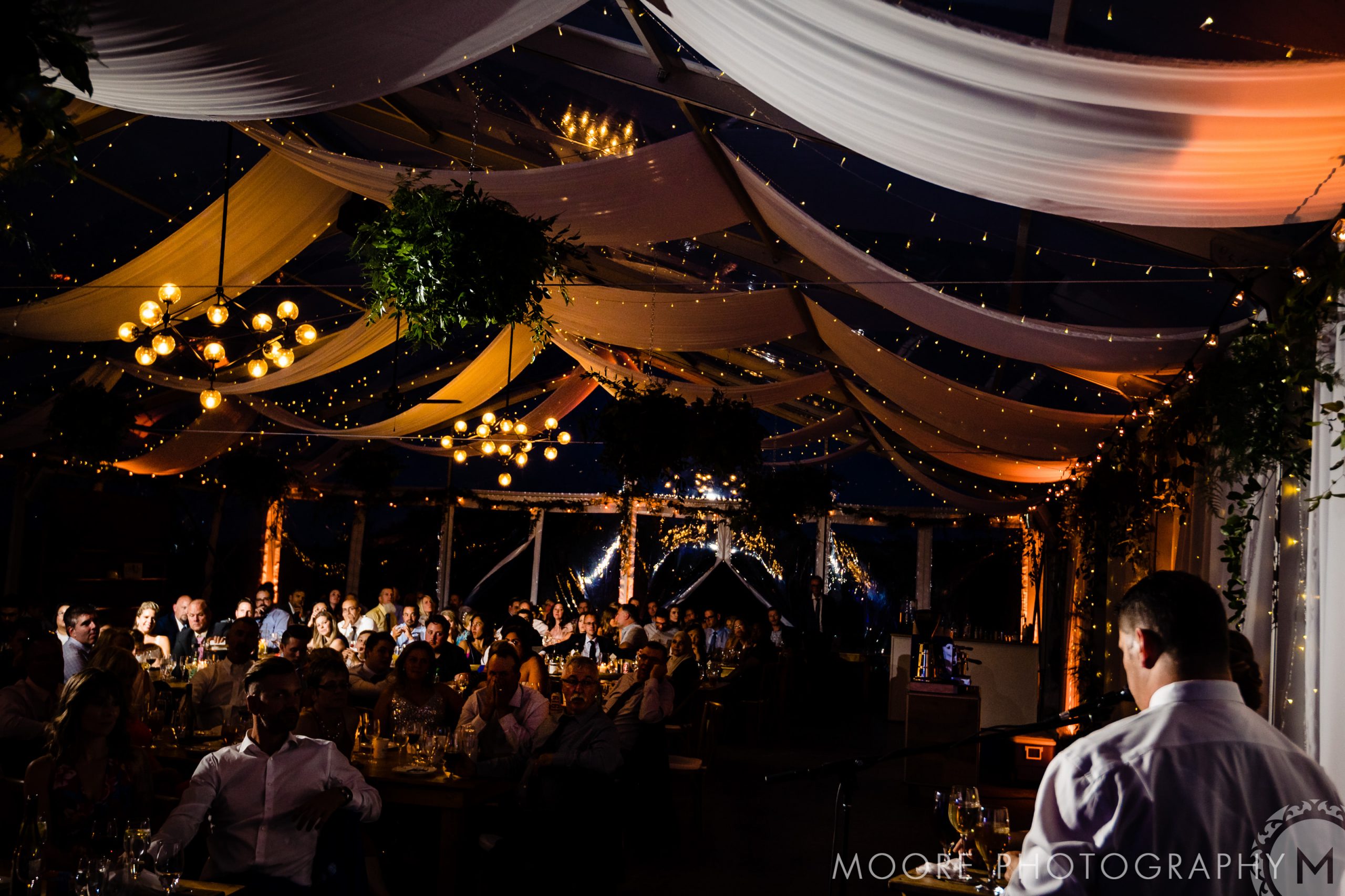 Indoor Winnipeg wedding venue with dim lighting, draped fabric ceiling, and seated guests.