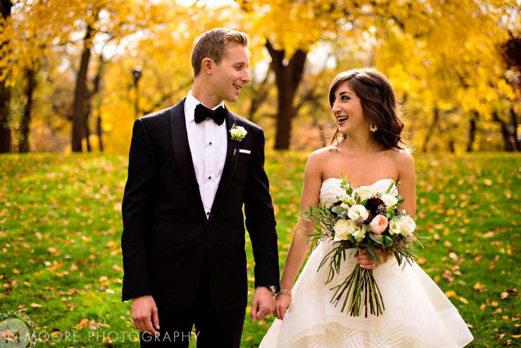 Bride and groom, and talking through a park with fall leaves everywhere