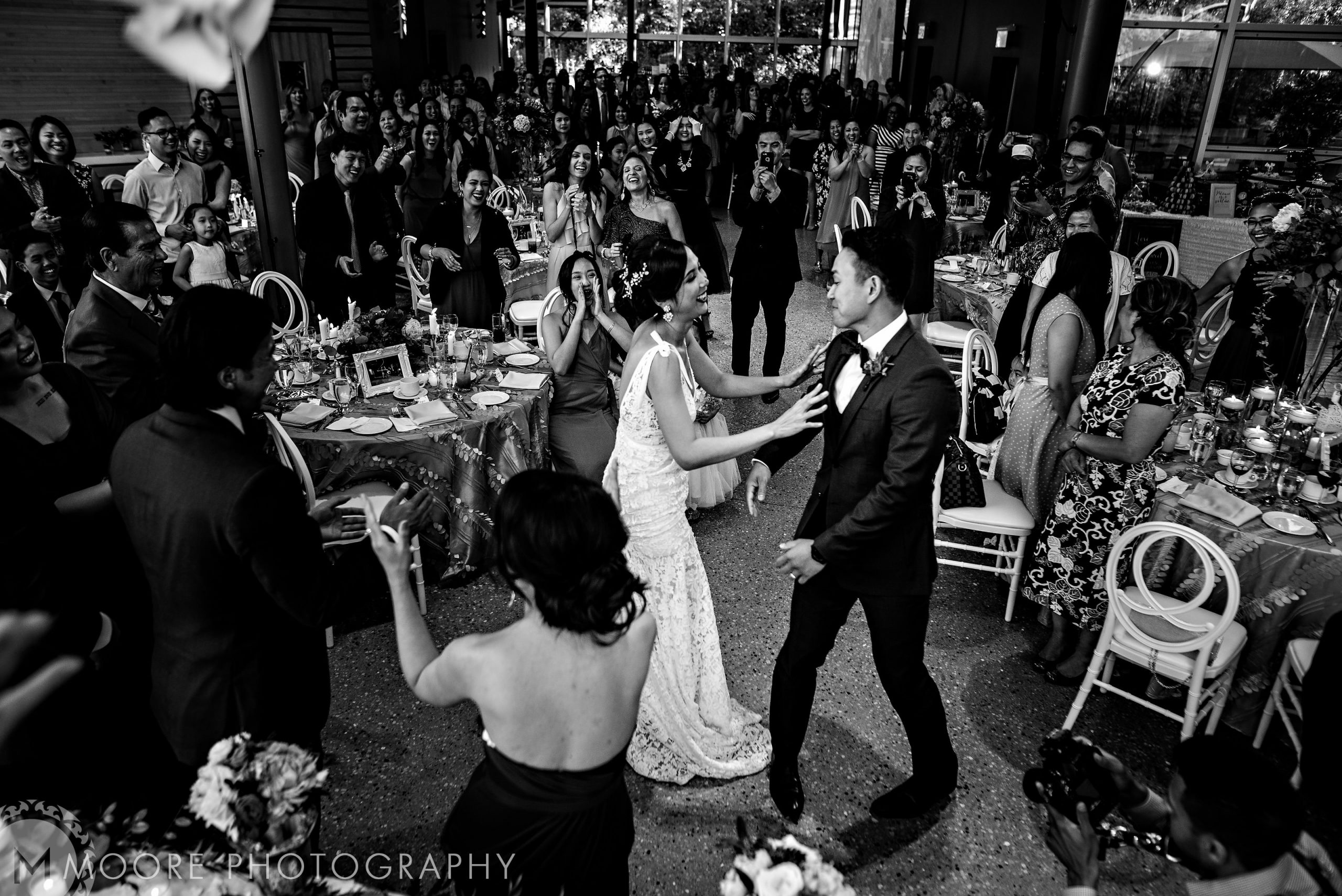 Bride and groom dance joyfully in Winnipeg wedding venues, cheered by lively guests.