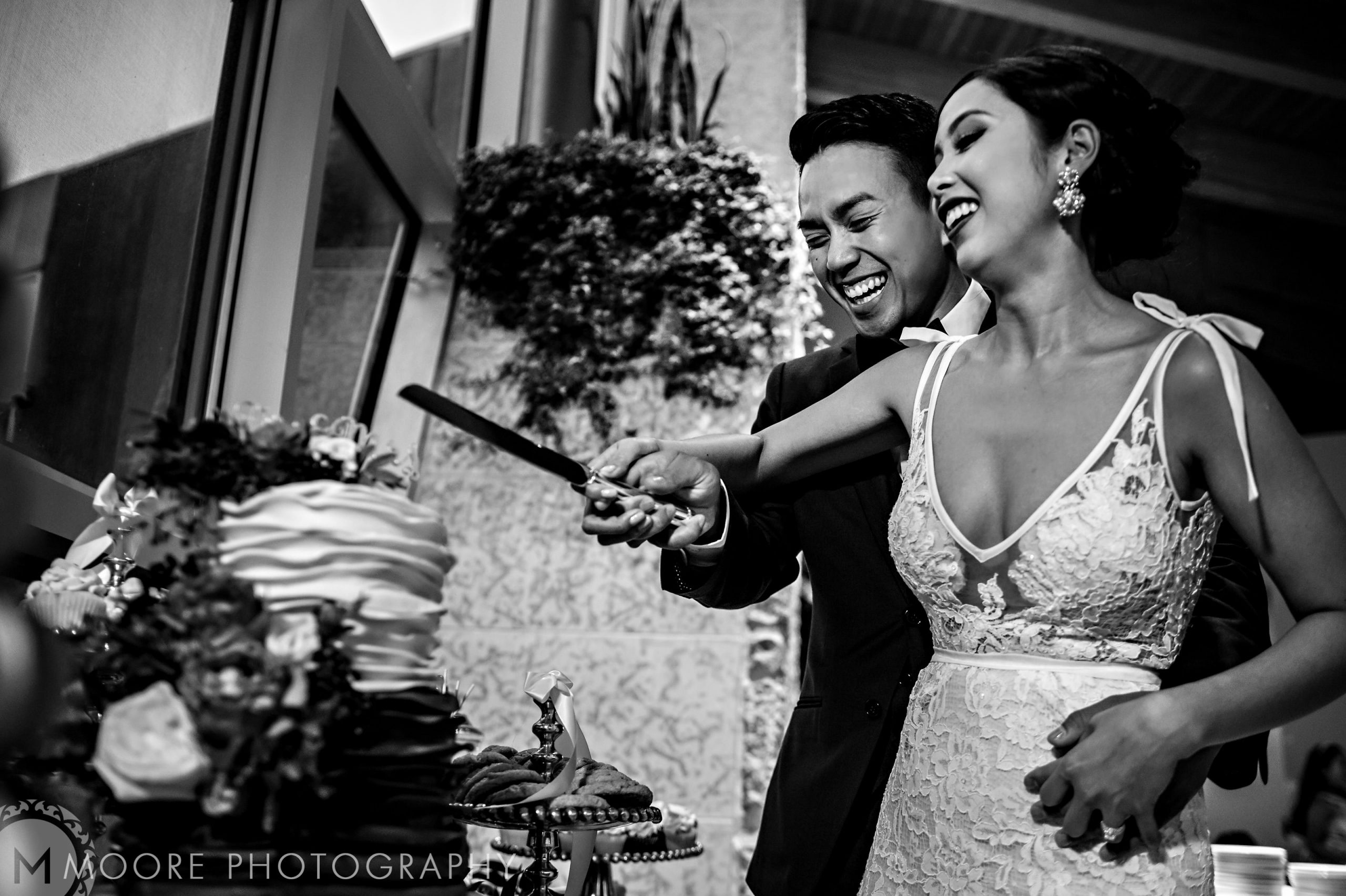 Couple joyfully cutting wedding cake at an elegant Winnipeg wedding venue.