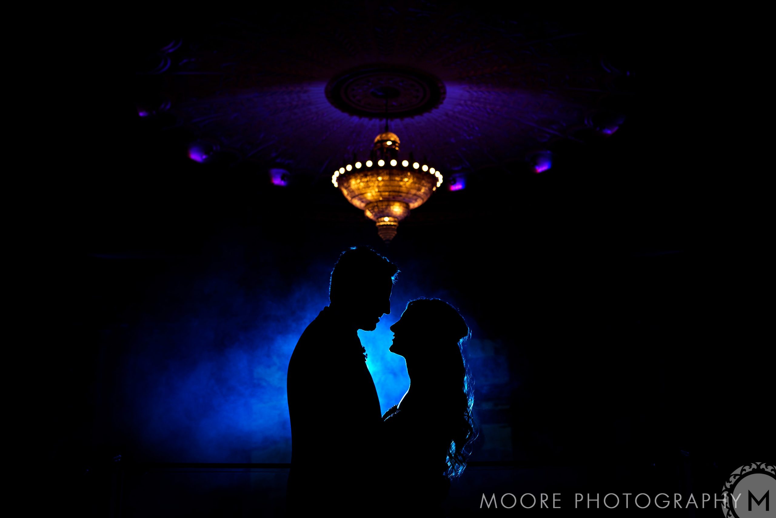 Silhouetted couple under a glowing chandelier at a Winnipeg wedding venue.
