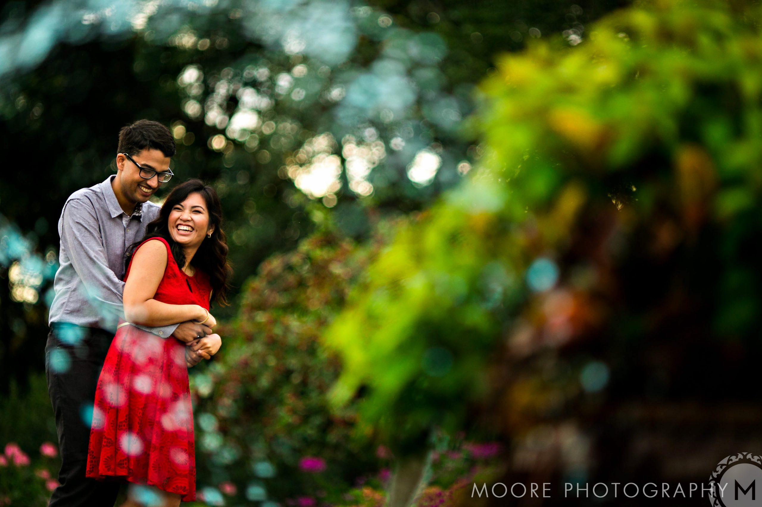 A couple laughing in a garden, capturing relaxed Winnipeg engagement vibes.