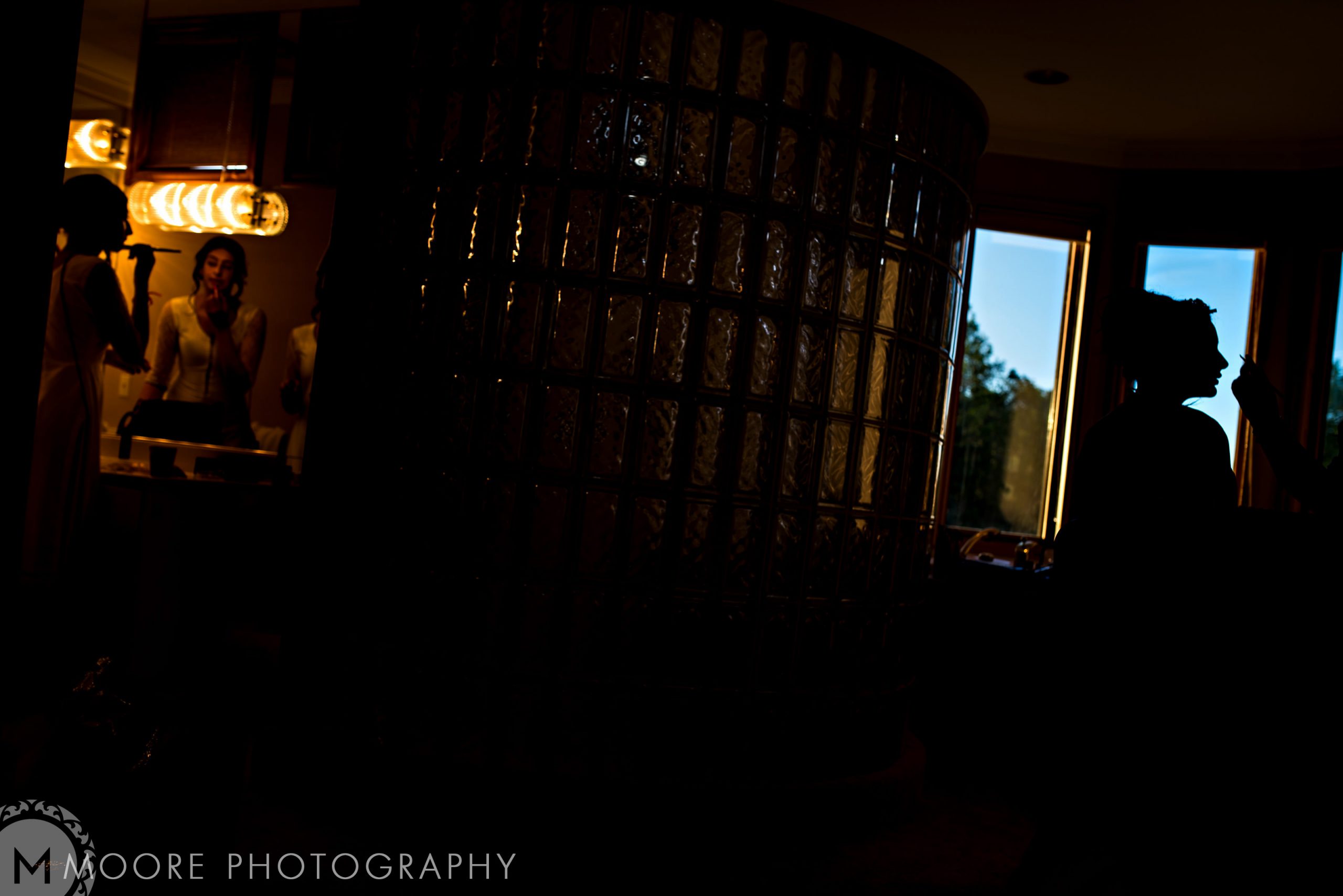 Silhouetted figures at Indian wedding, light from window and vanity mirror; photo by M. Moore.