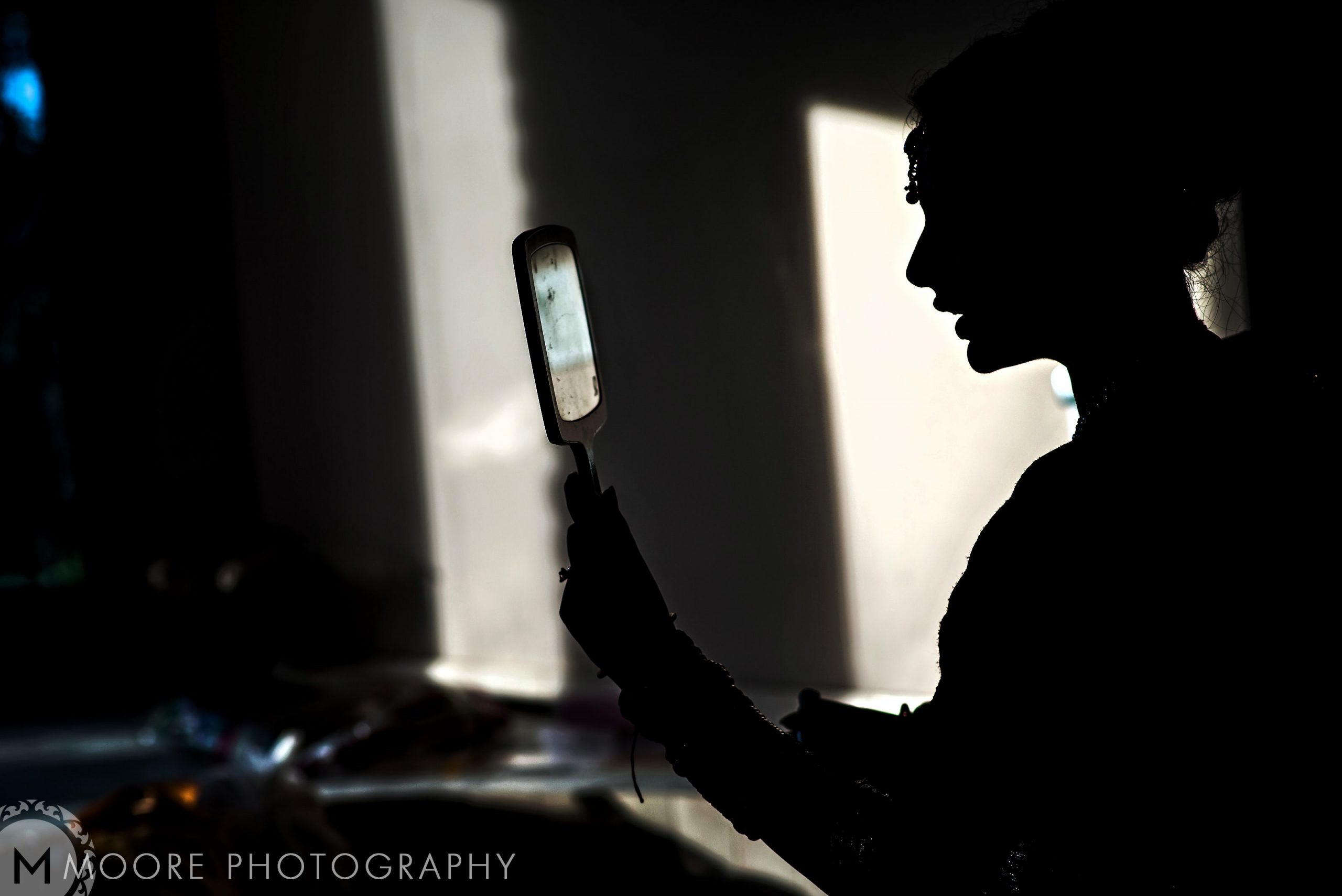 Silhouette of a person with a mirror, like an Indian wedding shadow cast on the wall.