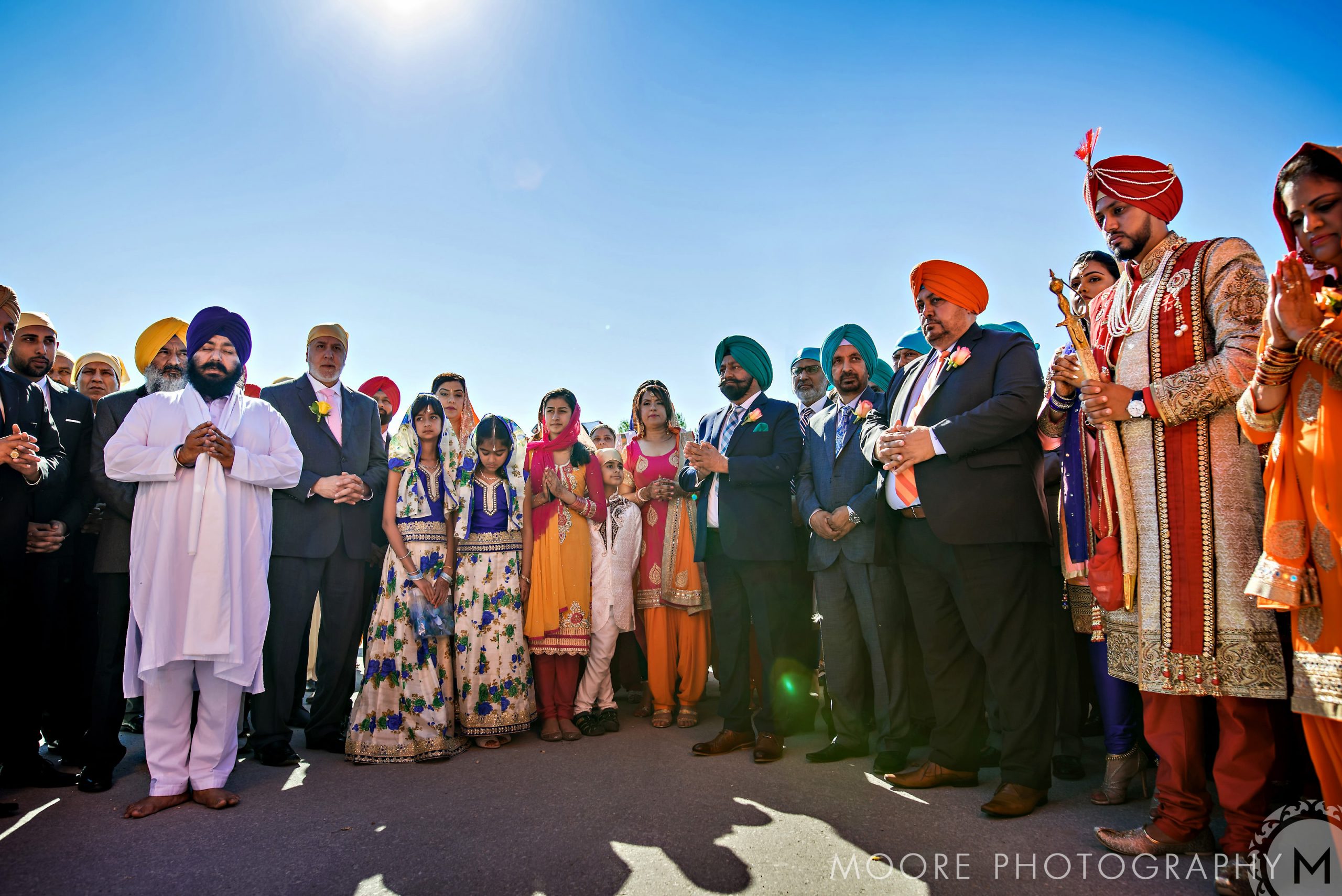 A group in traditional attire stands outdoors at an Indian wedding celebration.