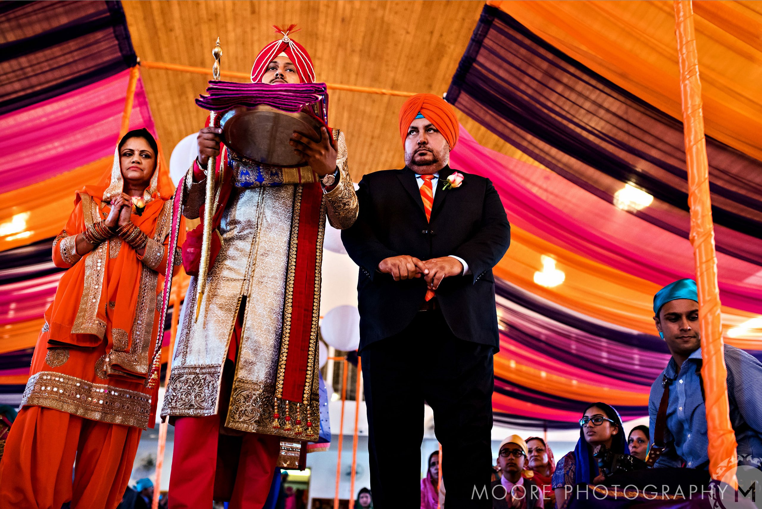 Indian wedding ceremony with vibrant drapes and traditionally dressed people.