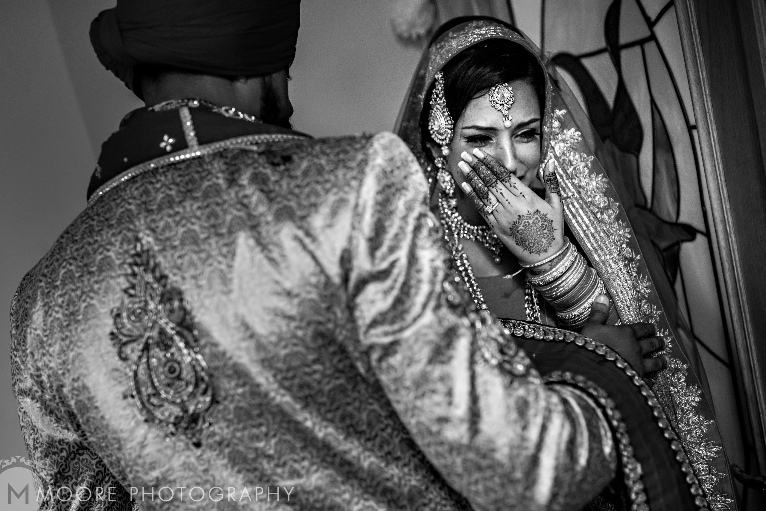 Bride laughing at an Indian wedding in traditional attire and jewelry.