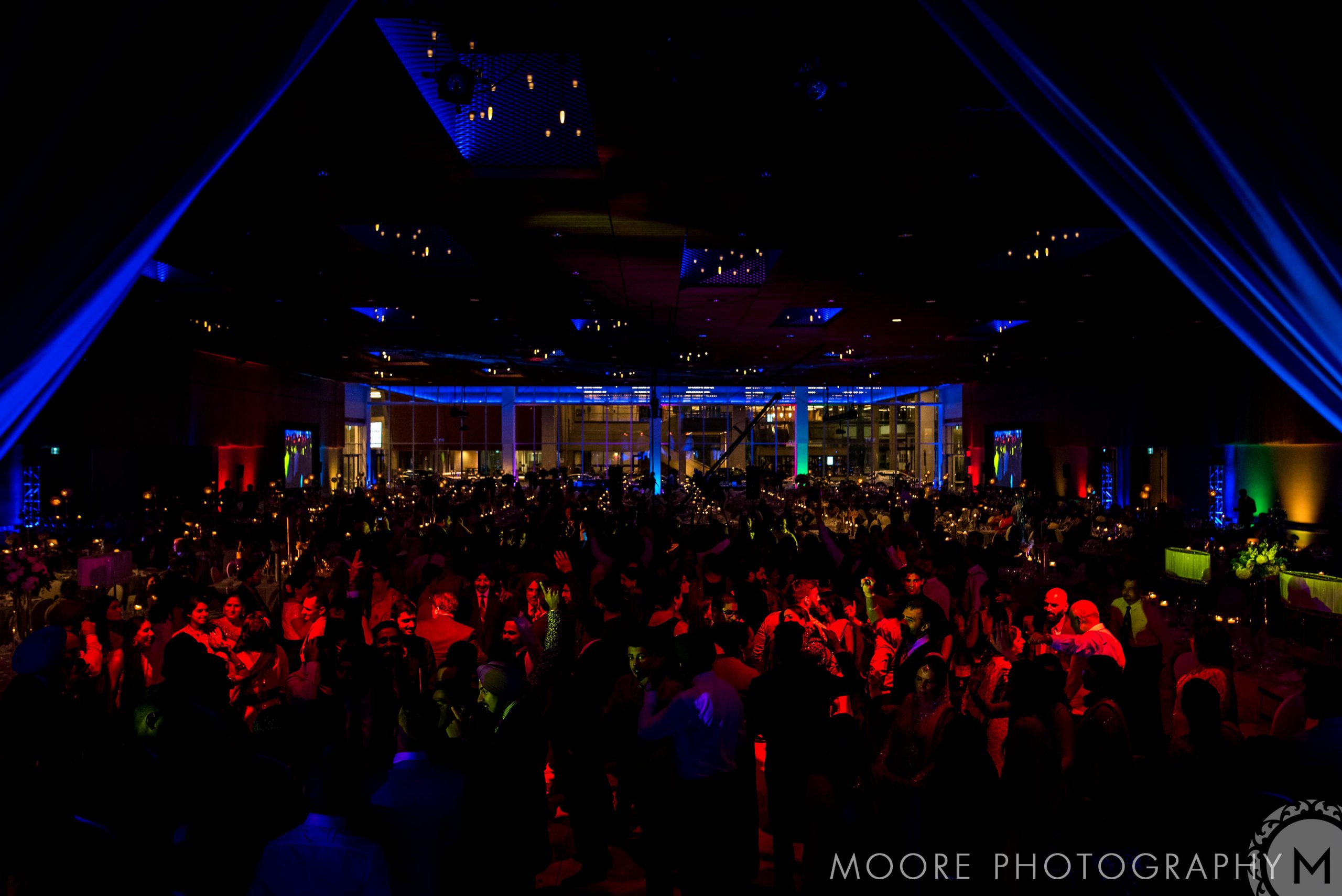 Lively Indian wedding with colorful lighting and a bustling atmosphere.