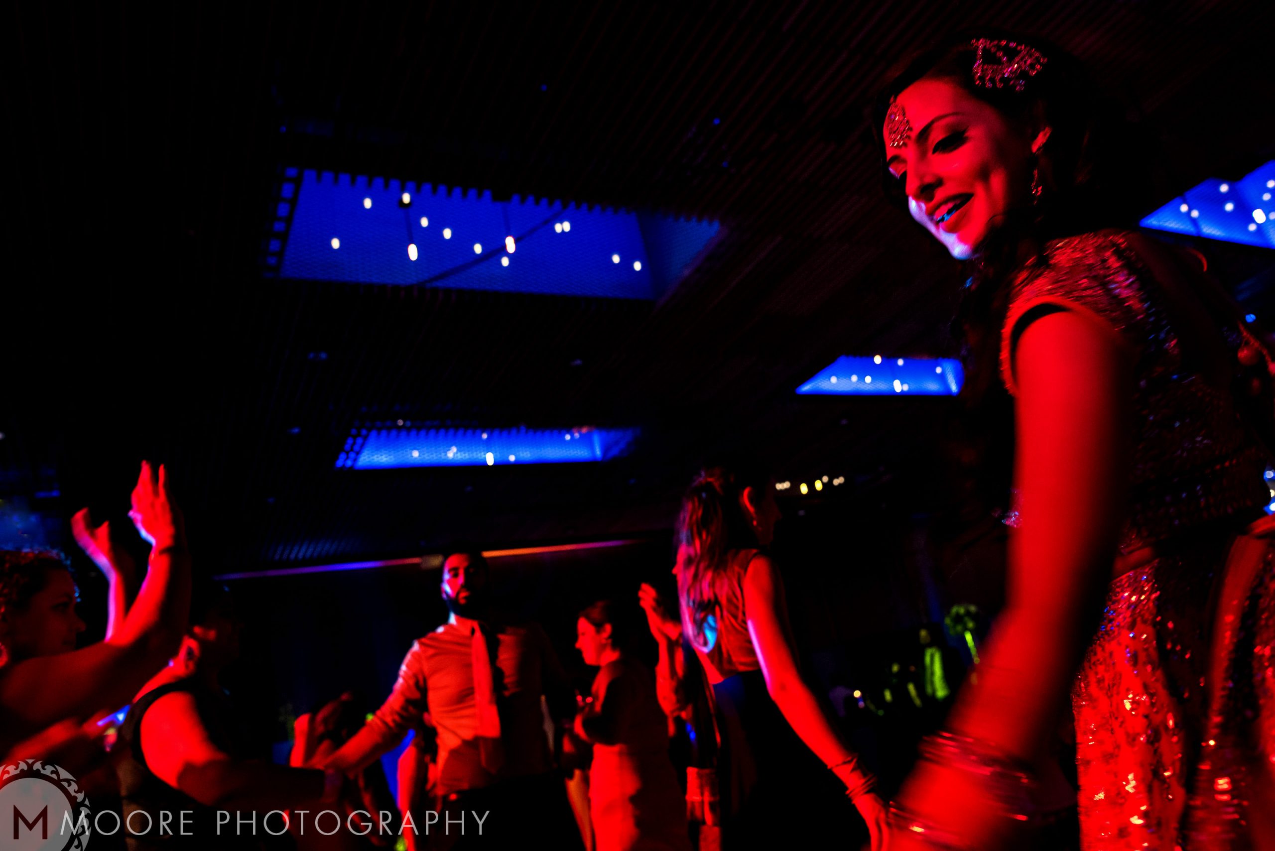 People dancing at a vibrant Indian wedding under twinkling lights.