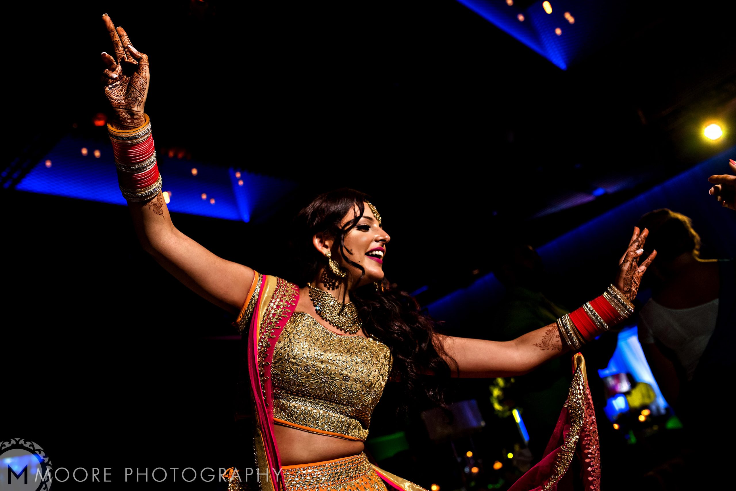 Woman in traditional attire dancing joyfully at a lively Indian wedding.