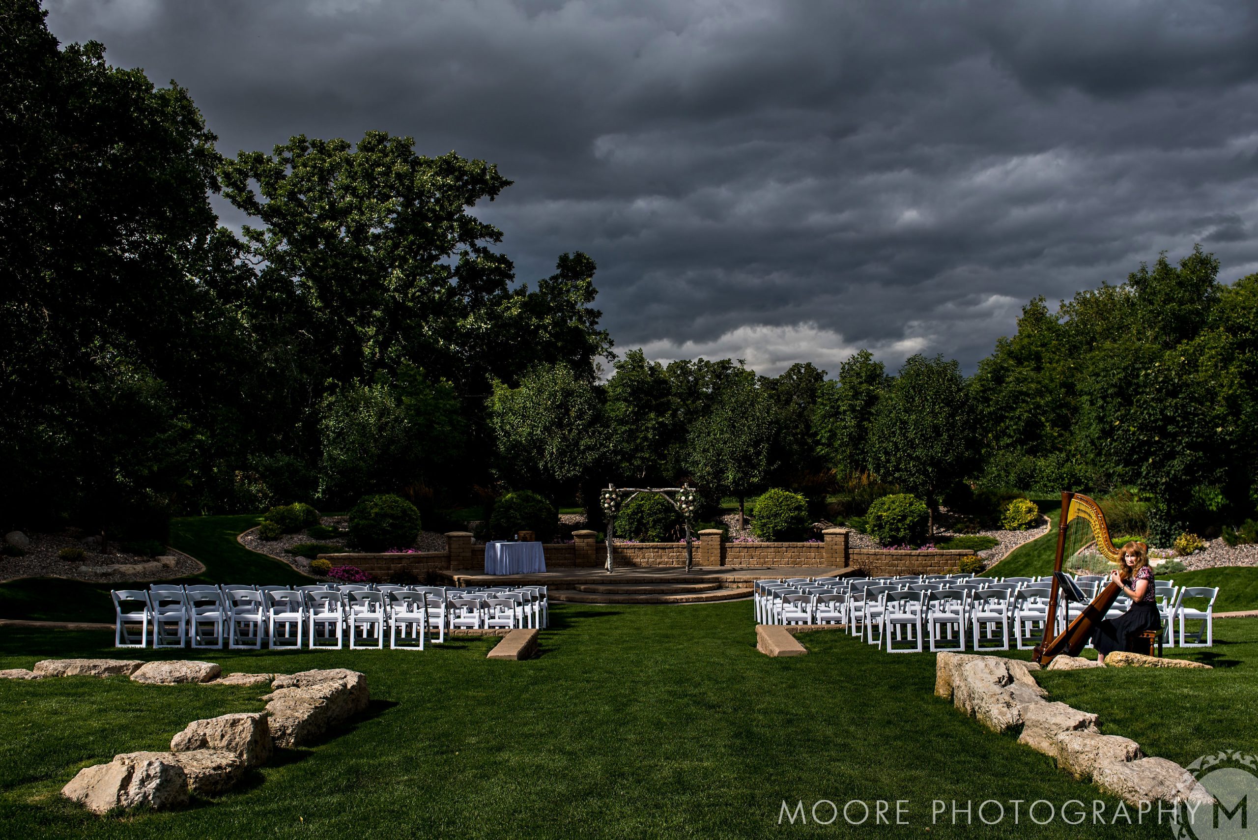 Winnipeg wedding venue with white chairs, dramatic clouds, and a harpist on the right.