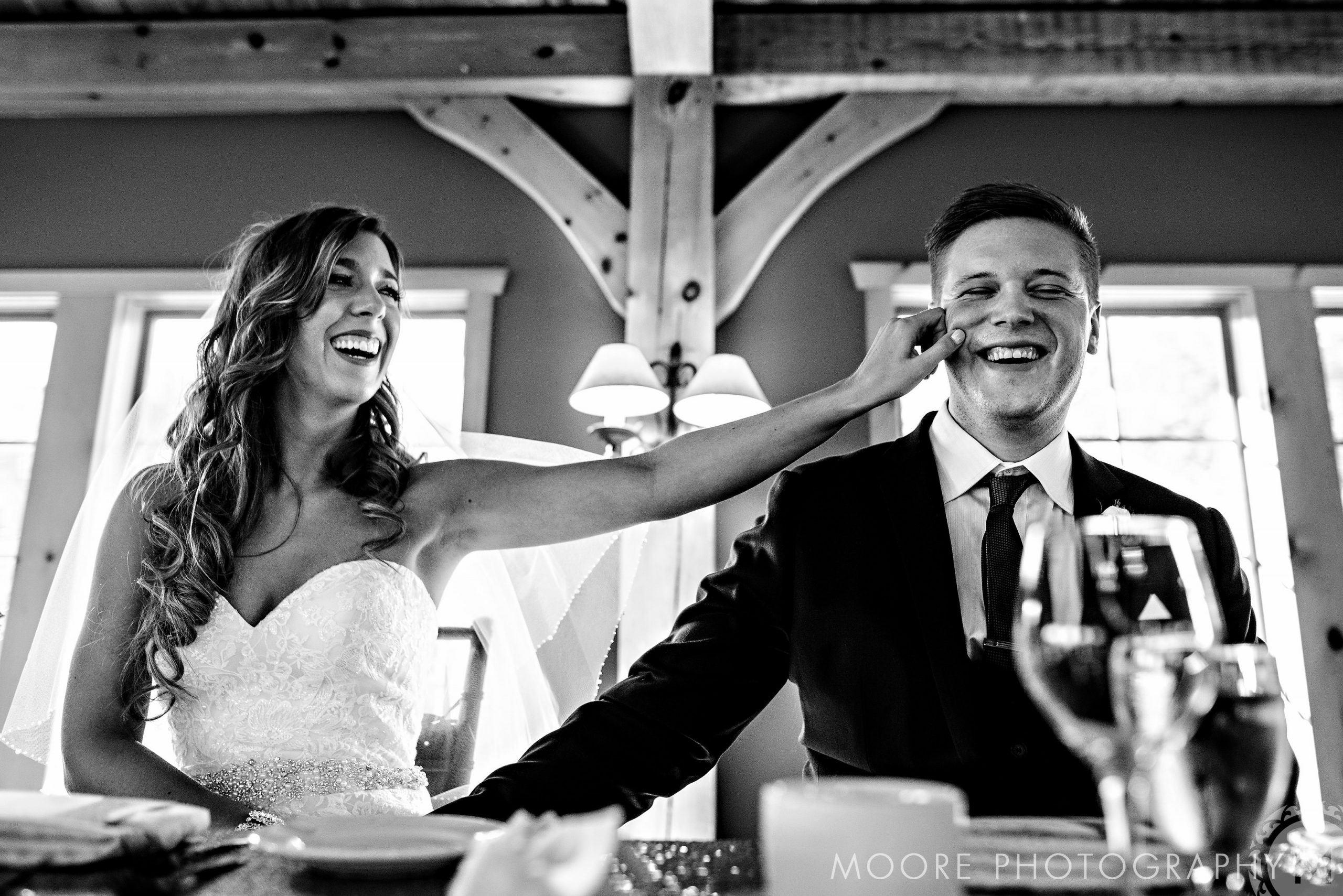 Bride playfully touches groom's face, both laughing at Winnipeg wedding reception.