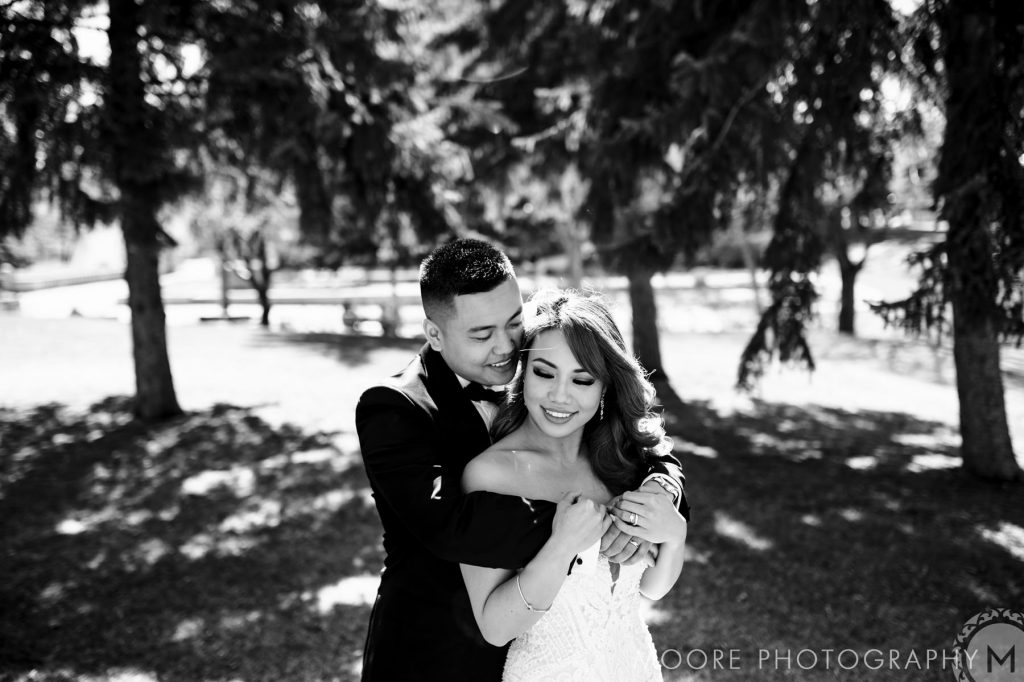Bride and groom, embracing and smiling for a wedding photo in a park in Winnipeg Manitoba