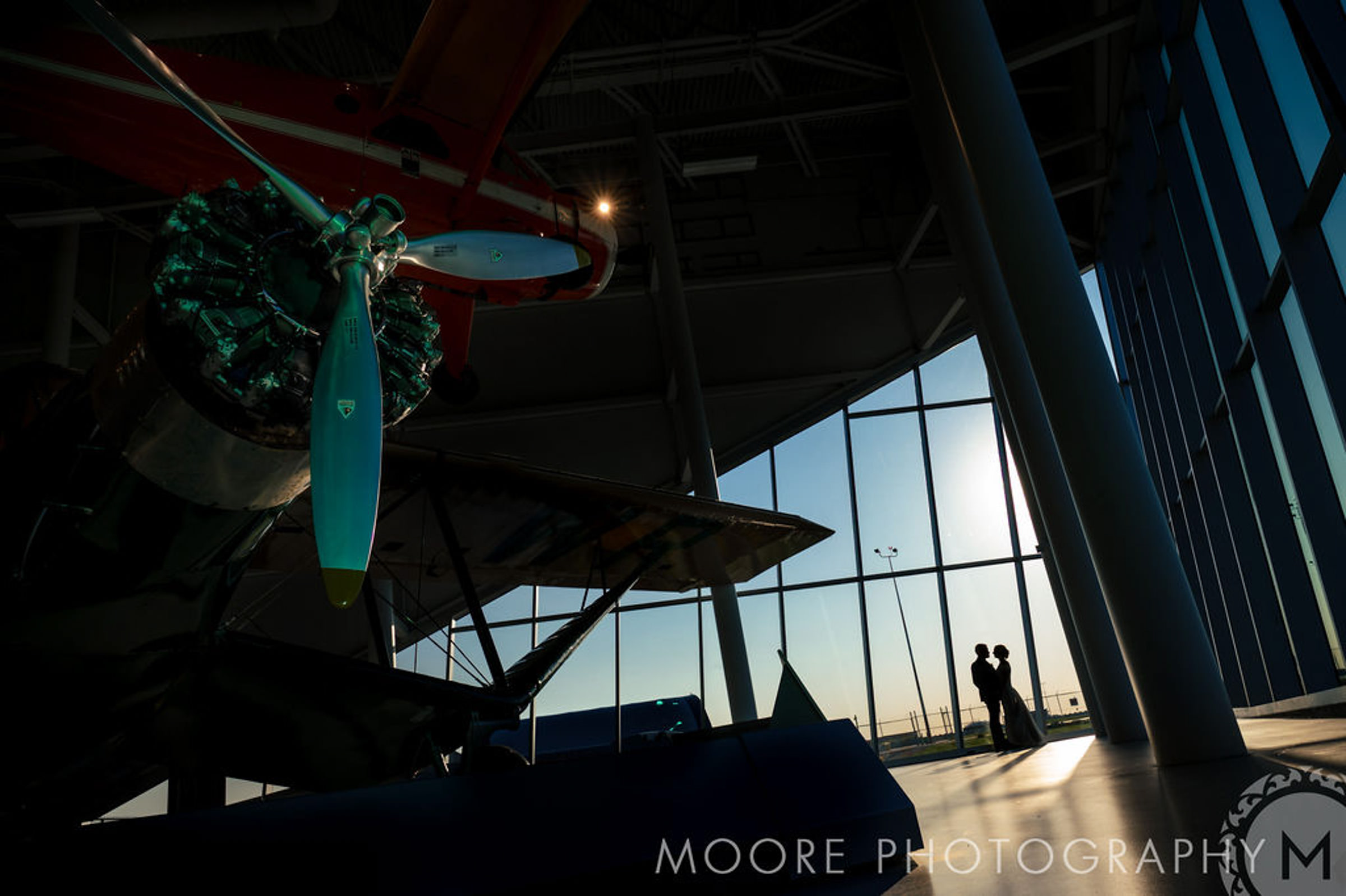 Airplane display indoors with silhouettes at Winnipeg wedding venues' large windows.