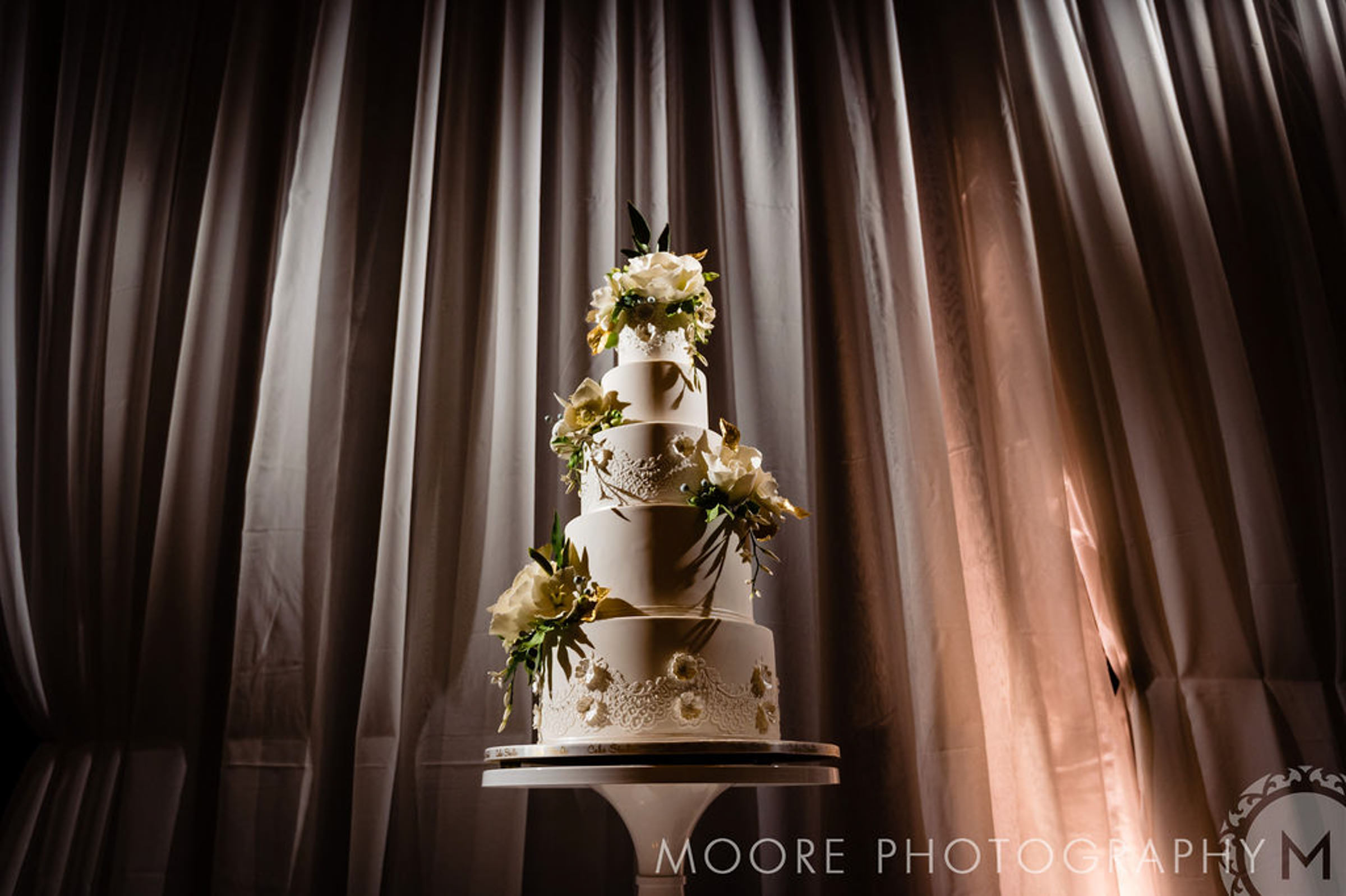 Four-tiered white wedding cake with floral accents at awe-inspiring Winnipeg wedding venues.
