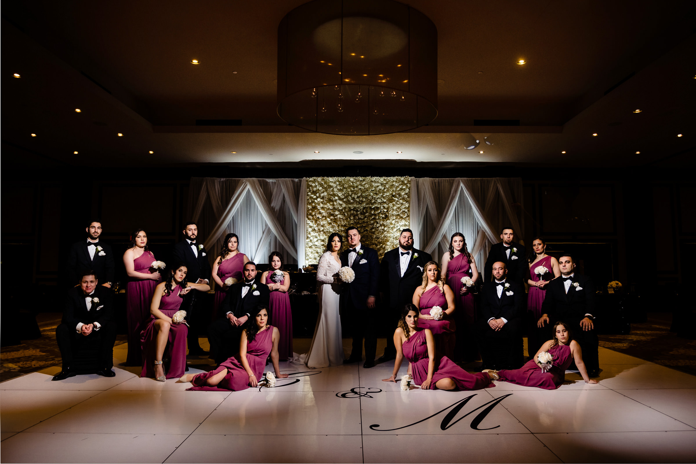 A wedding party in Winnipeg poses; bridesmaids in purple, groomsmen in black suits.
