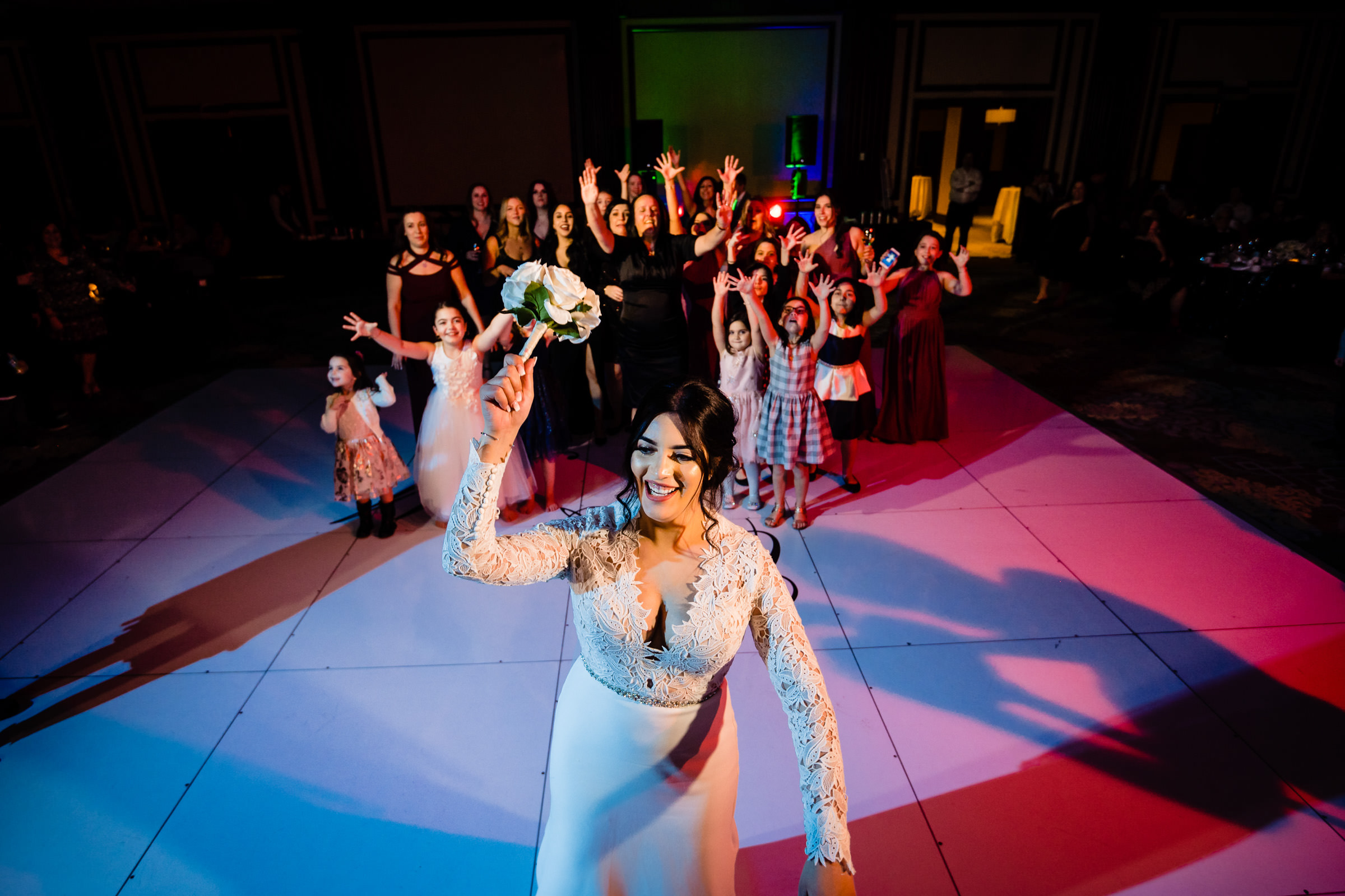 Bride tossing bouquet at Winnipeg wedding venues to an excited group of women and girls.