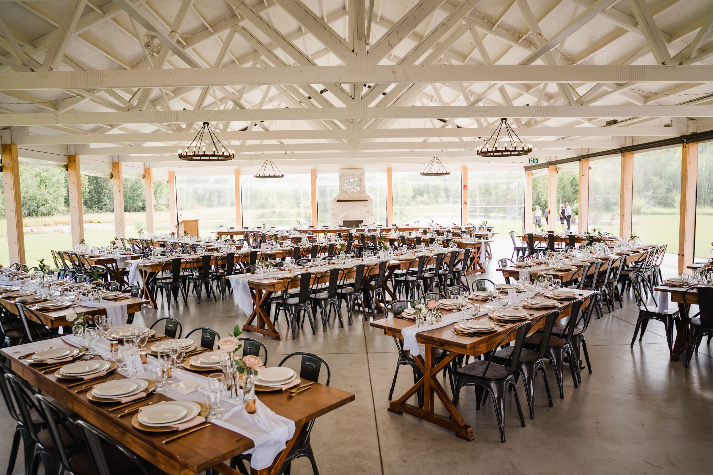 Rustic wedding reception venue with wooden tables set for guests.