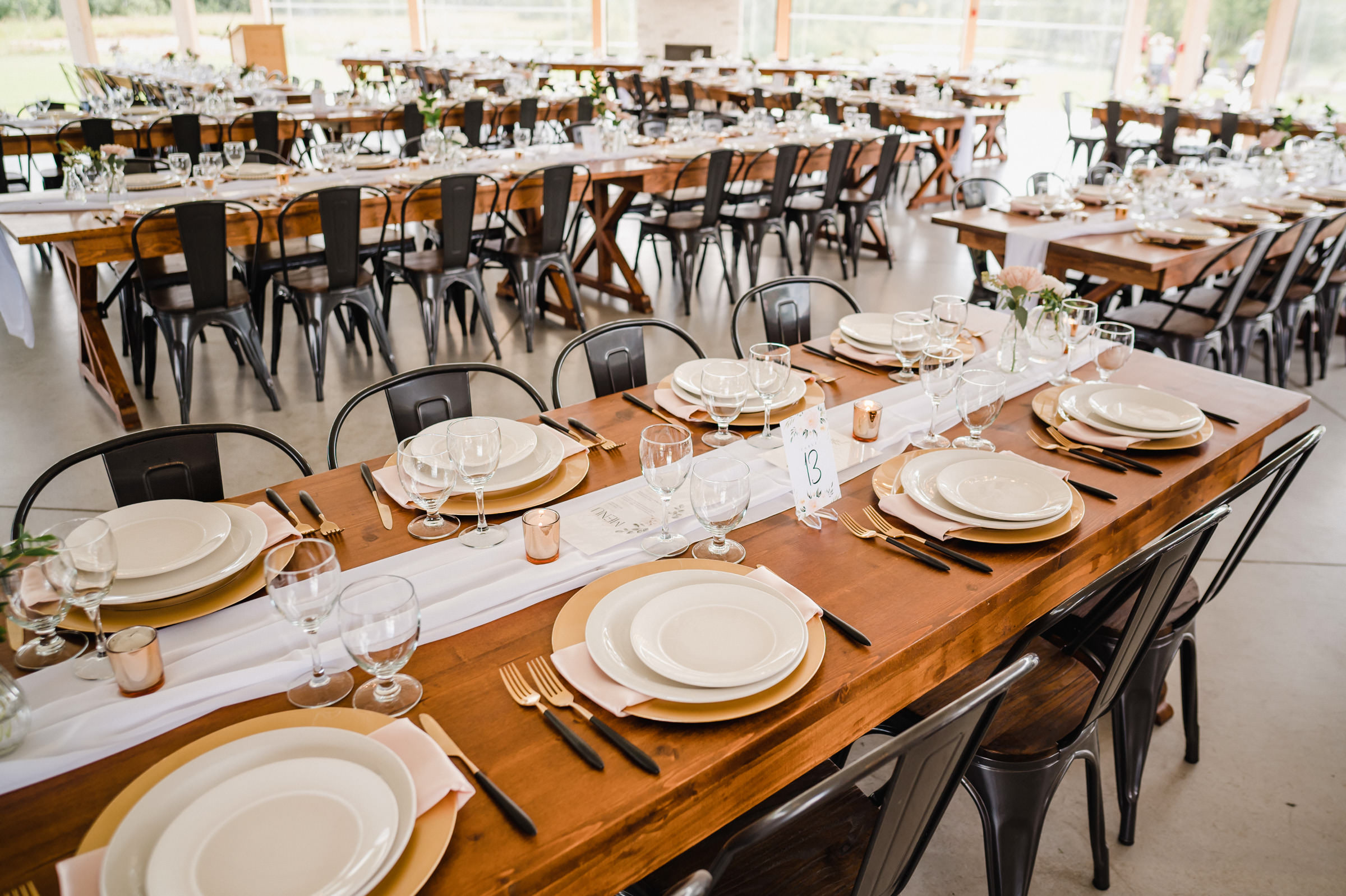 Elegant wedding reception setup at a Winnipeg venue with wooden tables and metal chairs.