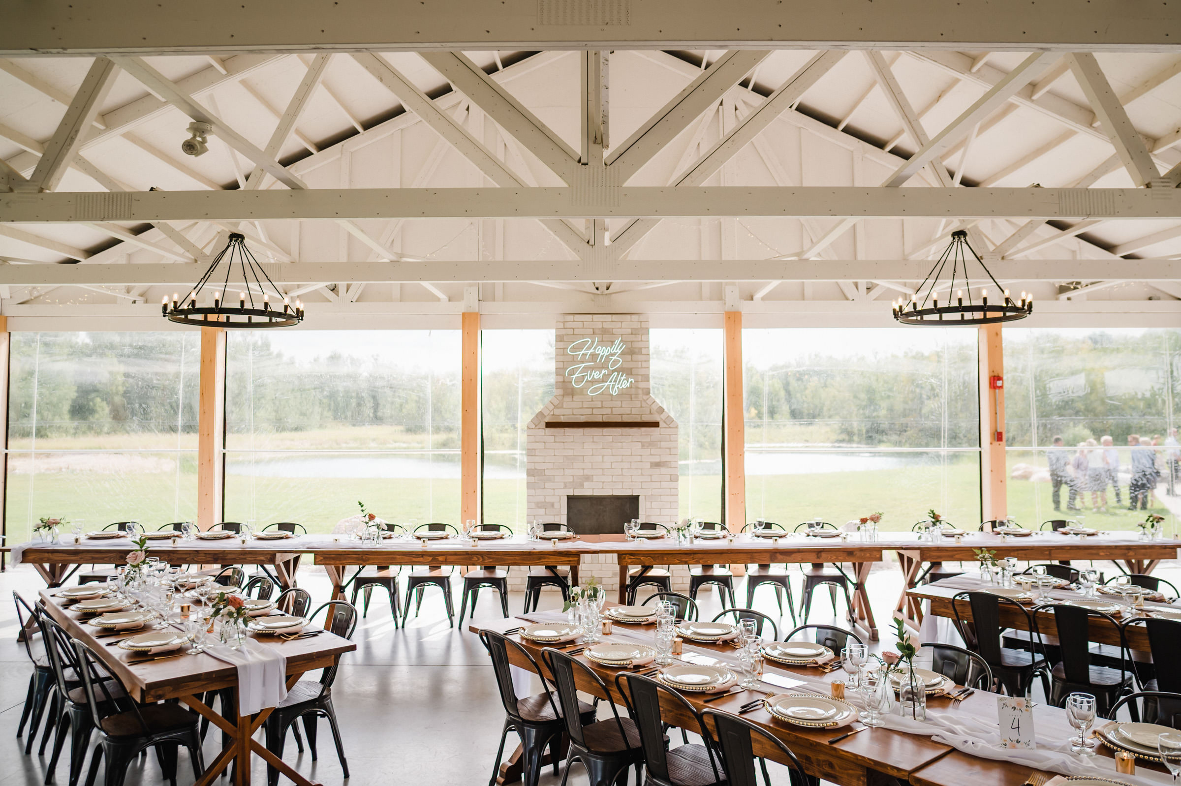 Rustic Winnipeg wedding venue with long tables, wooden beams, and lush greenery views.