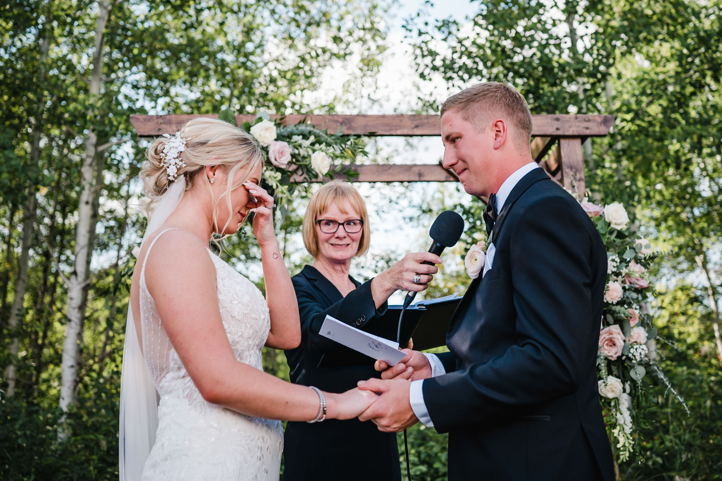 Bride and groom exchanging vows outdoors at a beautiful Winnipeg wedding venue.