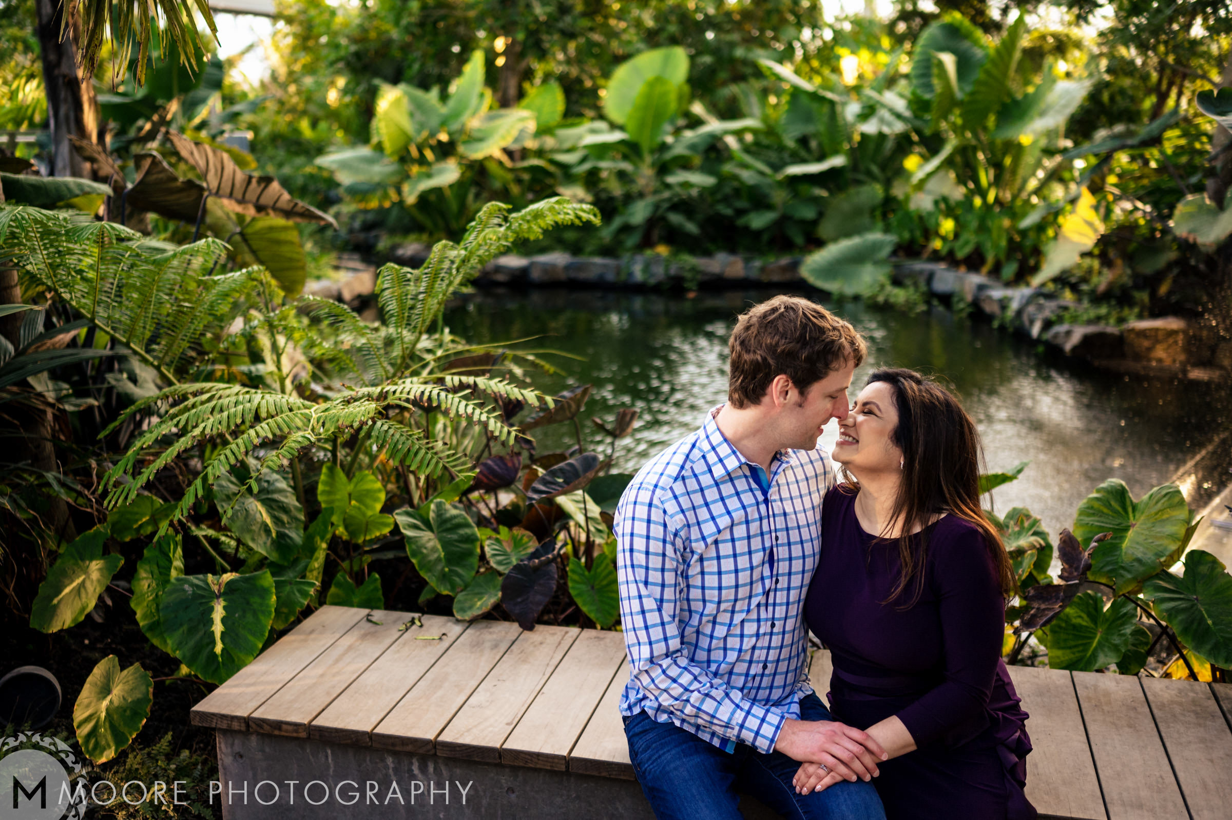 Couple sharing a loving gaze on a bench at one of Winnipeg's lush wedding venues.