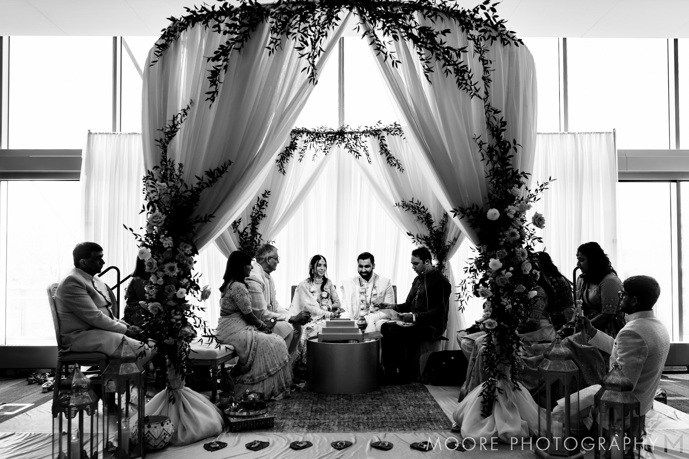 A Winnipeg wedding under a decorated canopy with guests seated, in black and white.