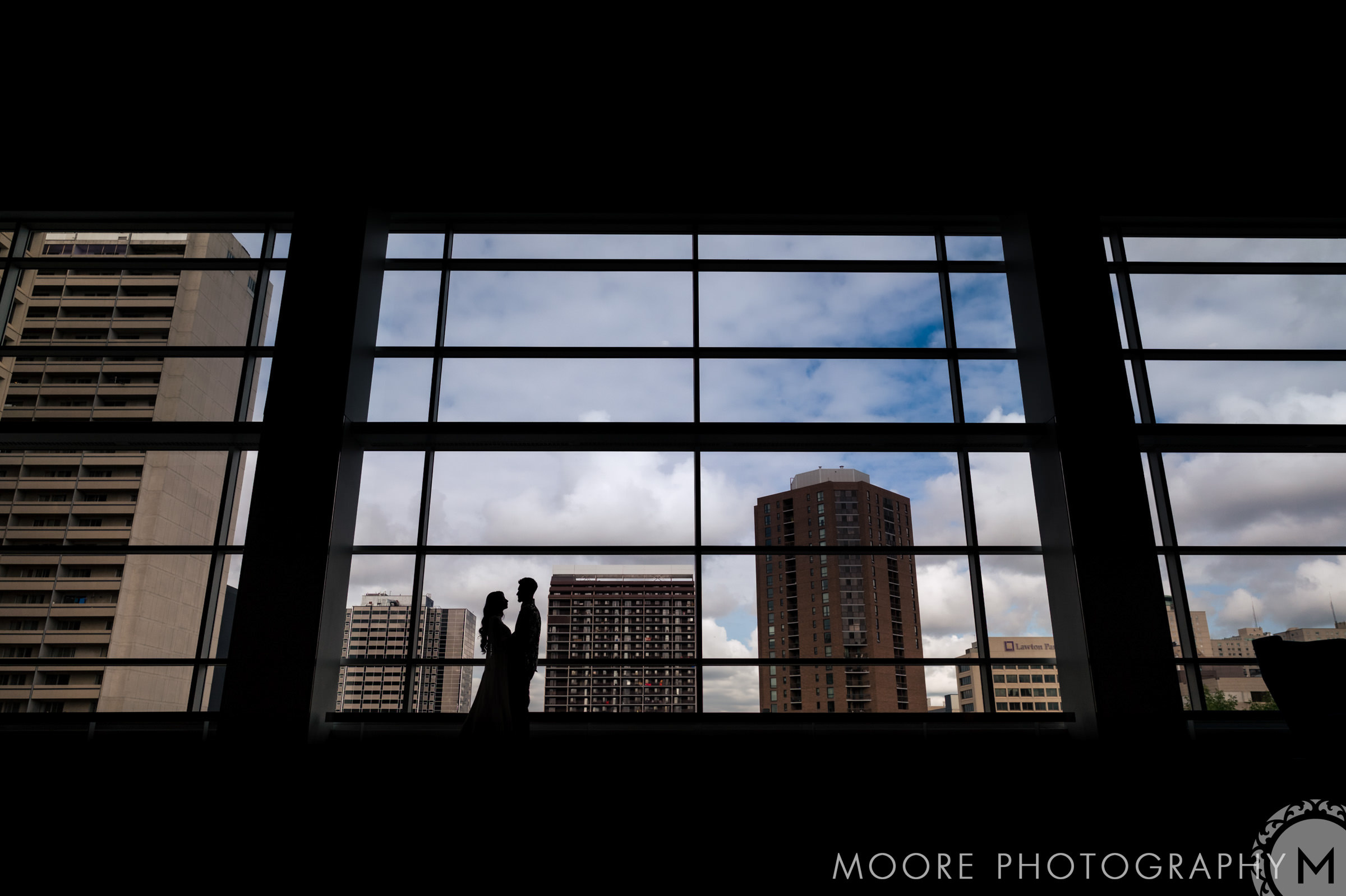 Silhouette of a couple in a Winnipeg wedding venue with a cityscape view.