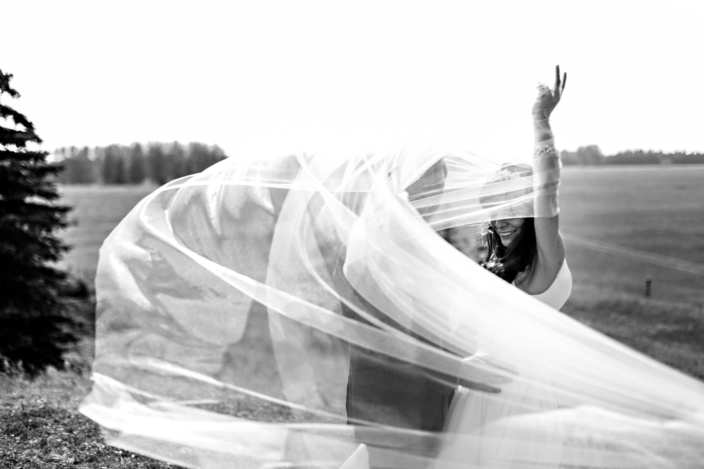 Bride and groom, embracing and flowing in the wind at Birdsill Park, Manitoba