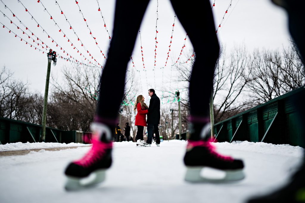 Engagement session, photo, with a couple skating pictured through the legs of another skater at the forks