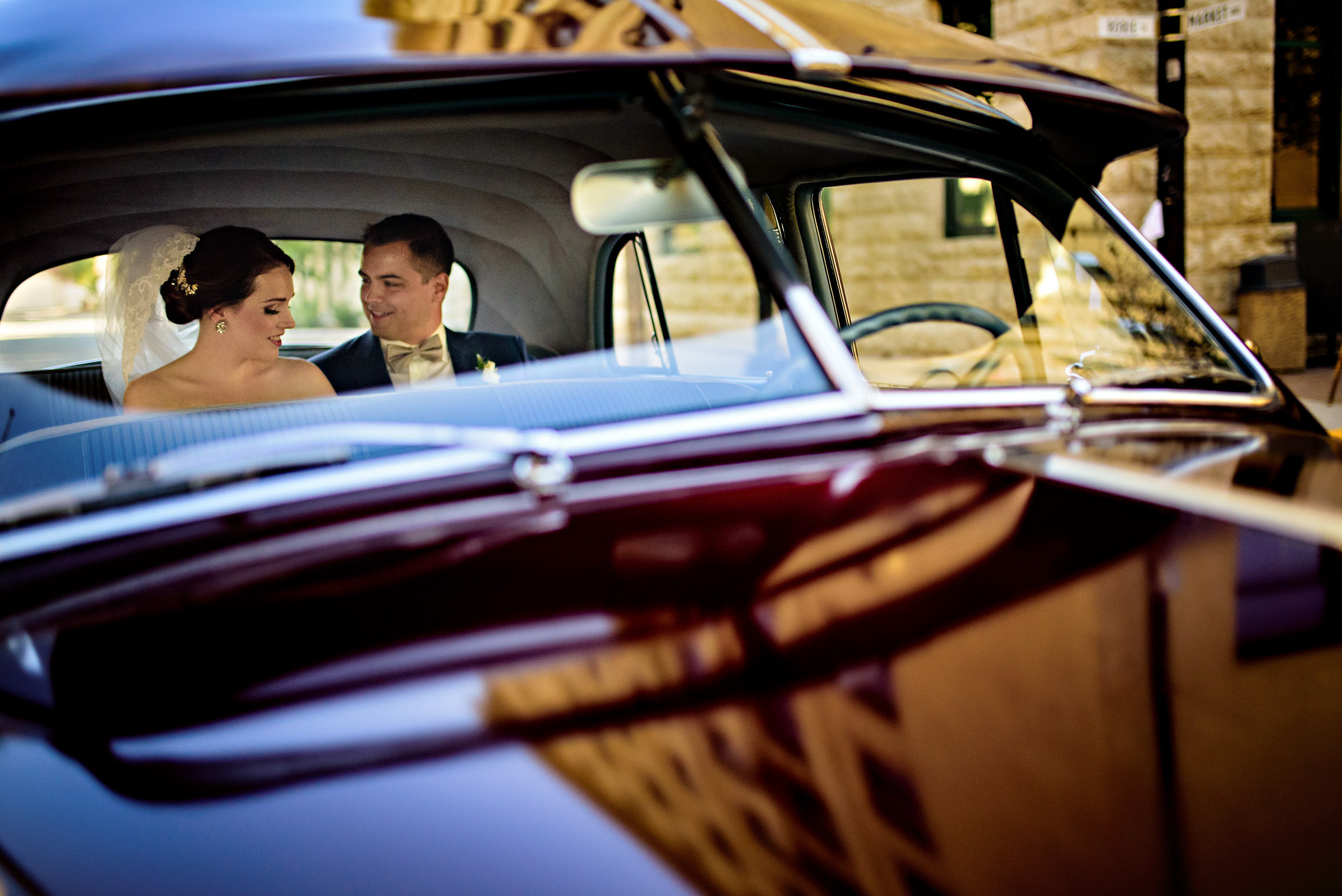a Bride and groom, sitting in the back of an old-fashioned car in Winnipeg Manitoba