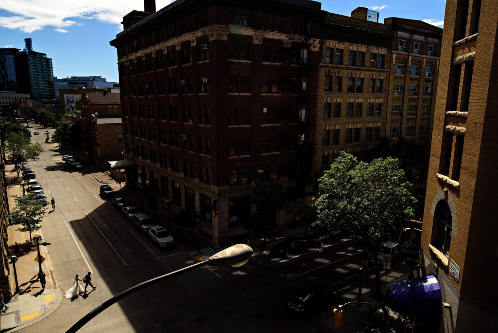Photograph taken on a building of a bride and groom walking across the street in downtown Winnipeg
