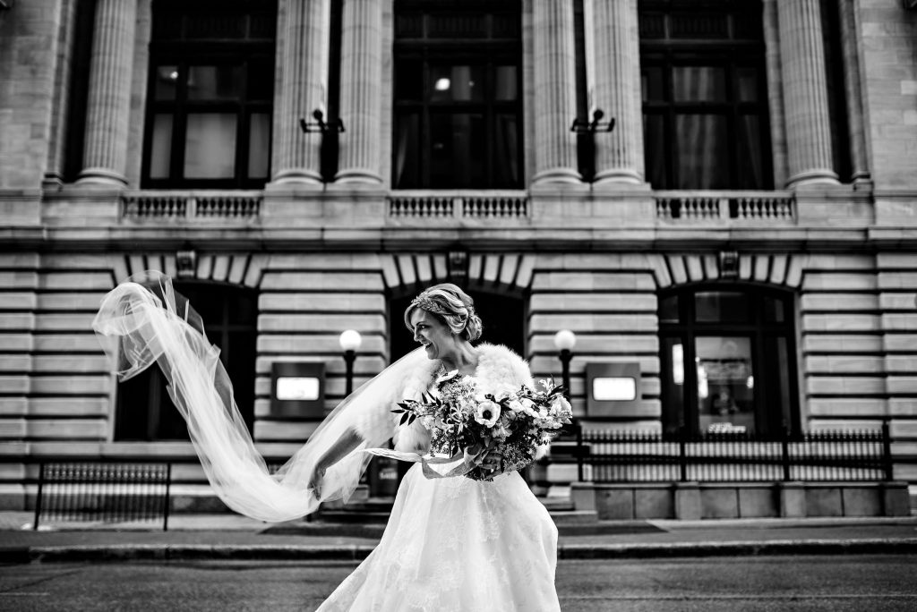 A Bride fixing her veil in front of a historic building in downtown Winnipeg