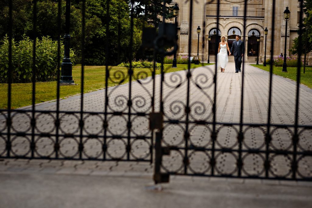 Bride and groom, walking from Saint Boniface Cathedral, holding hands through a gate