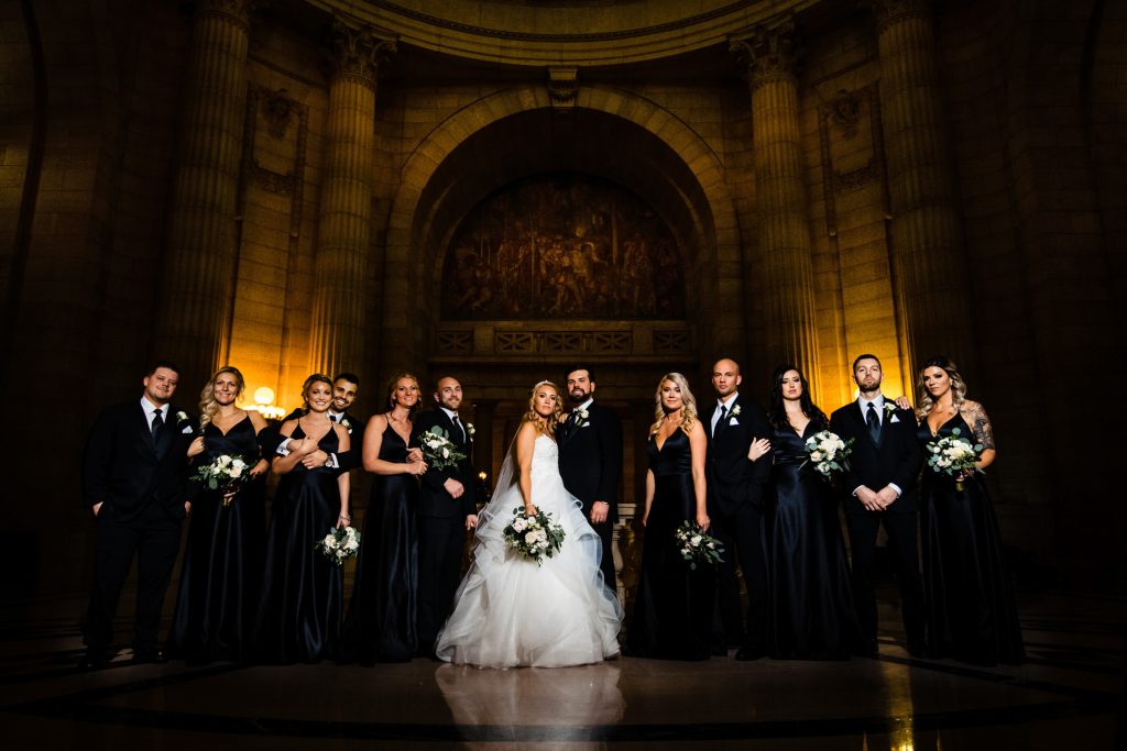 A bride and groom with their wedding party posing for a portrait at the Winnipeg legislative building