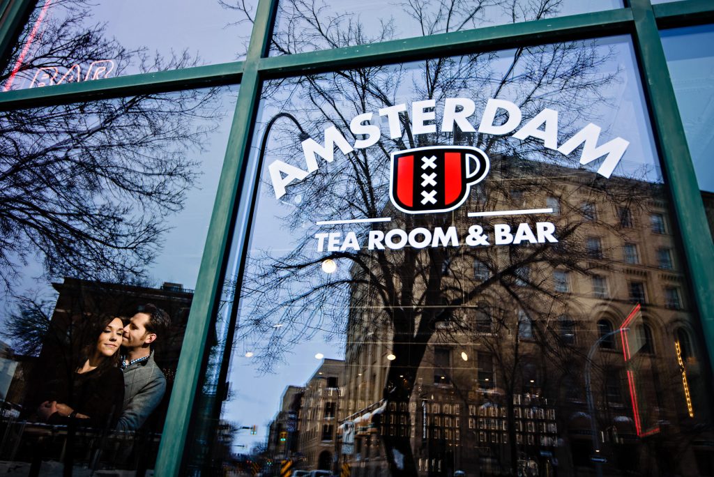 A couple posing during an engagement session in a window in the exchange in Winnipeg