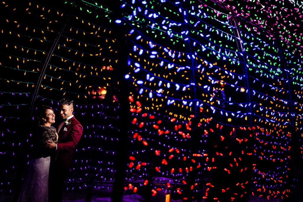 A couple, embracing and laughing in the cold winter Christmas lights at the forks