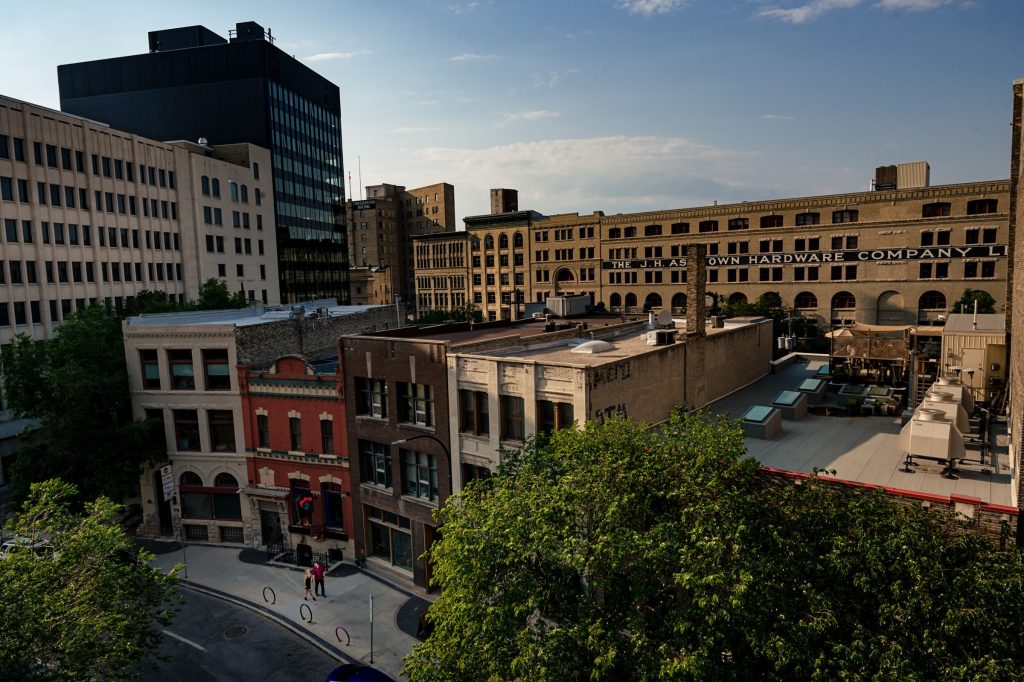 A couple walking together on a sidewalk downtown with buildings in the Winnipeg exchange district