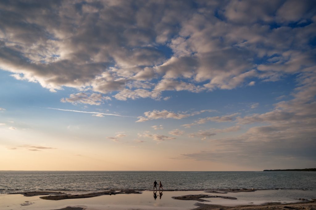 Running across the beach with a lake in the background for an engagement photo